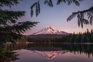 Snowy mountain reflected in calm lake waters.