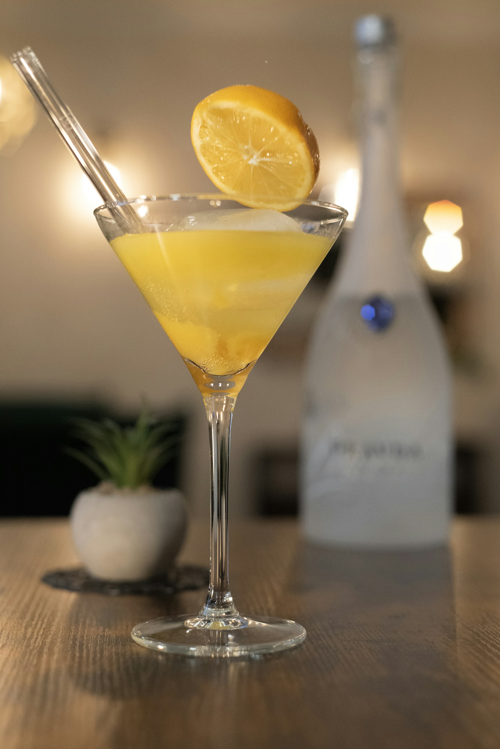 A lemon cocktail with a glass straw.