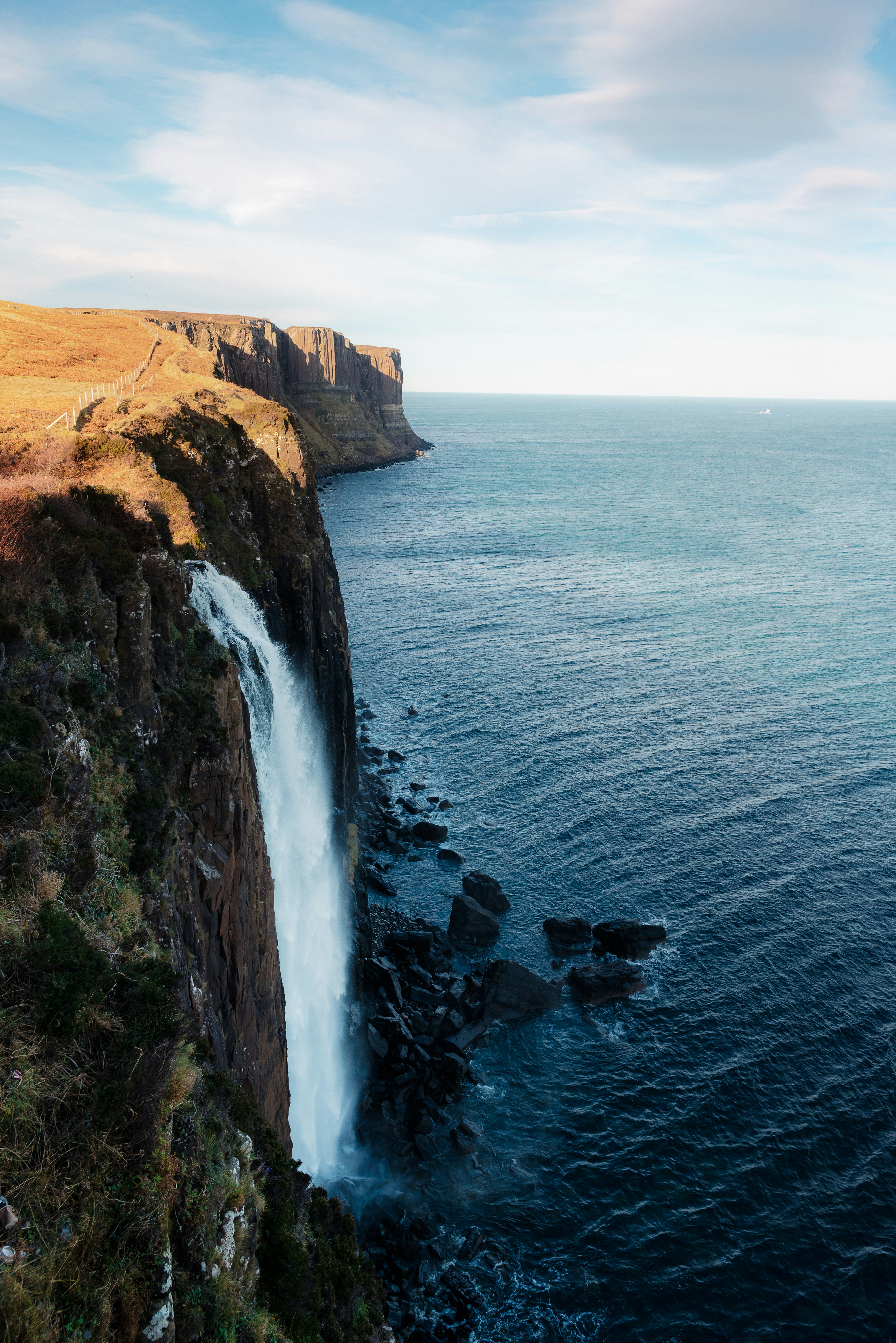 A waterfall cascades down a cliff into the sea.