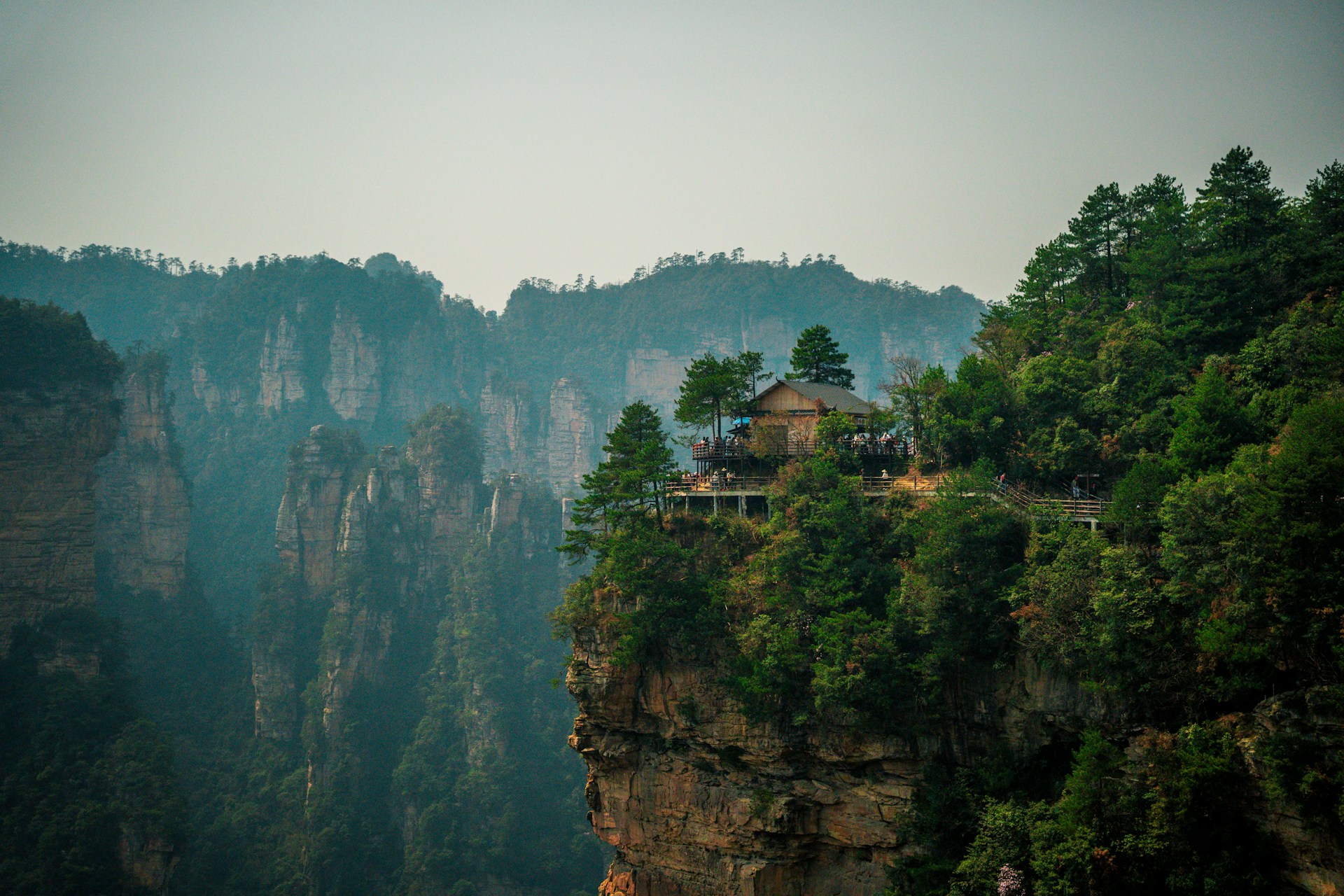A building sits atop a cliffside, overlooking mountains.