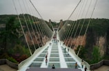 People walk across a glass bridge.