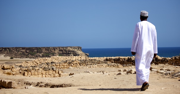Man walks towards the ocean in traditional attire.