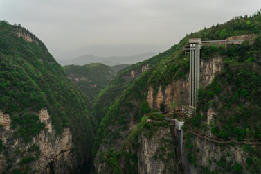 An elevator rises from a deep, green canyon.