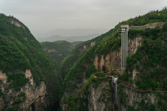 An elevator rises from a deep, green canyon.