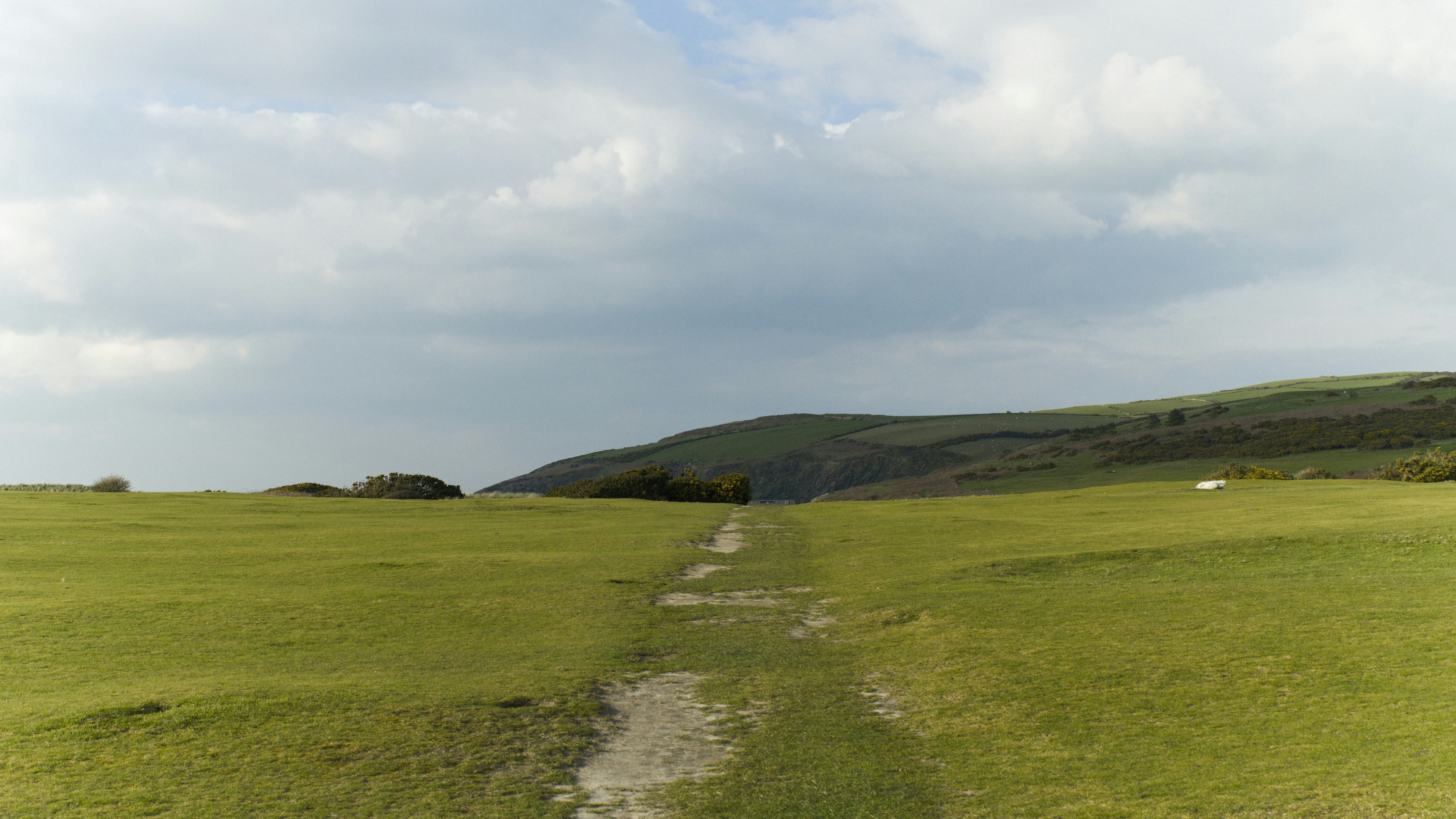 A grassy path leads toward a distant hill.