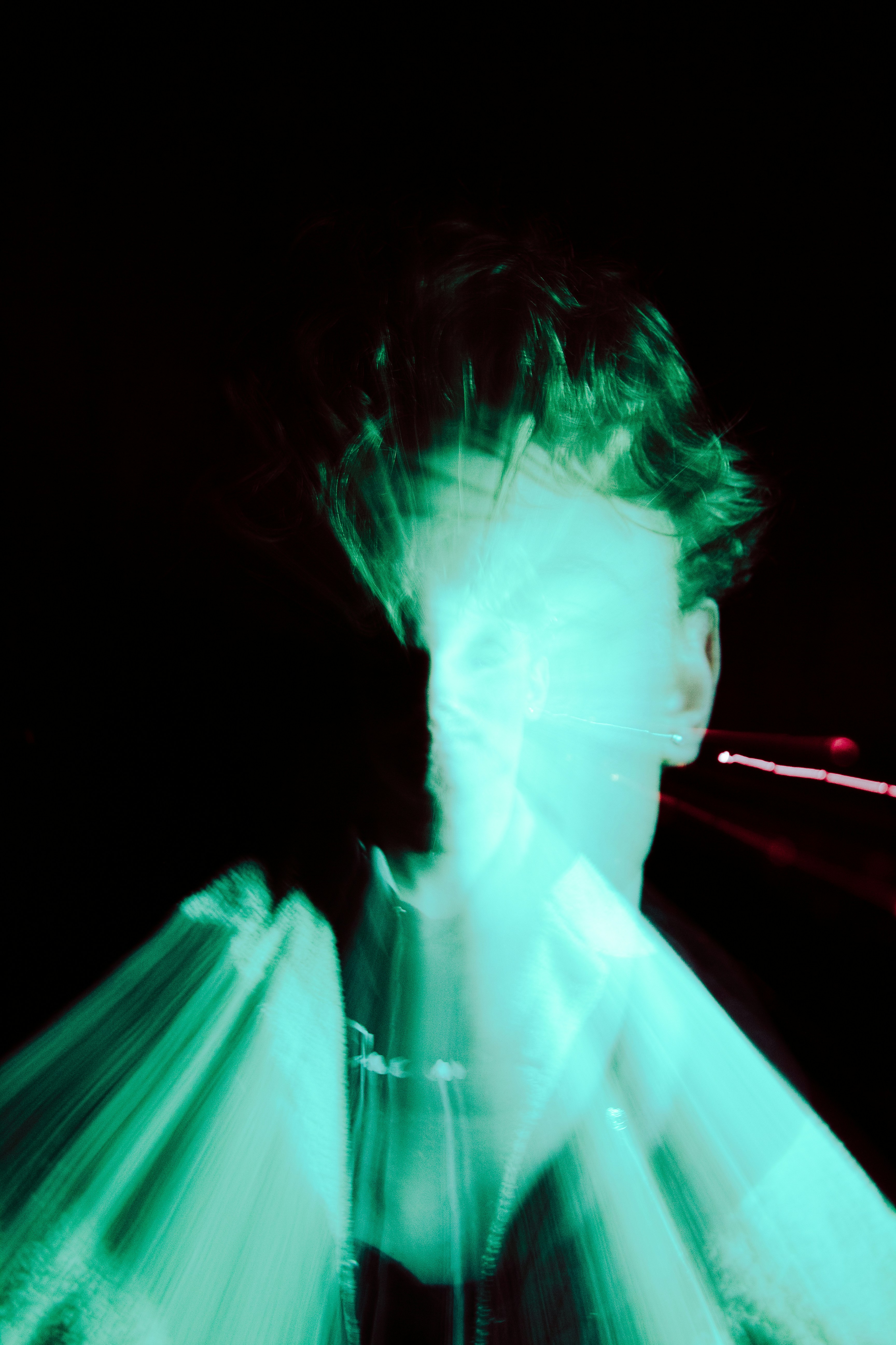 A blurred person glows with green light.