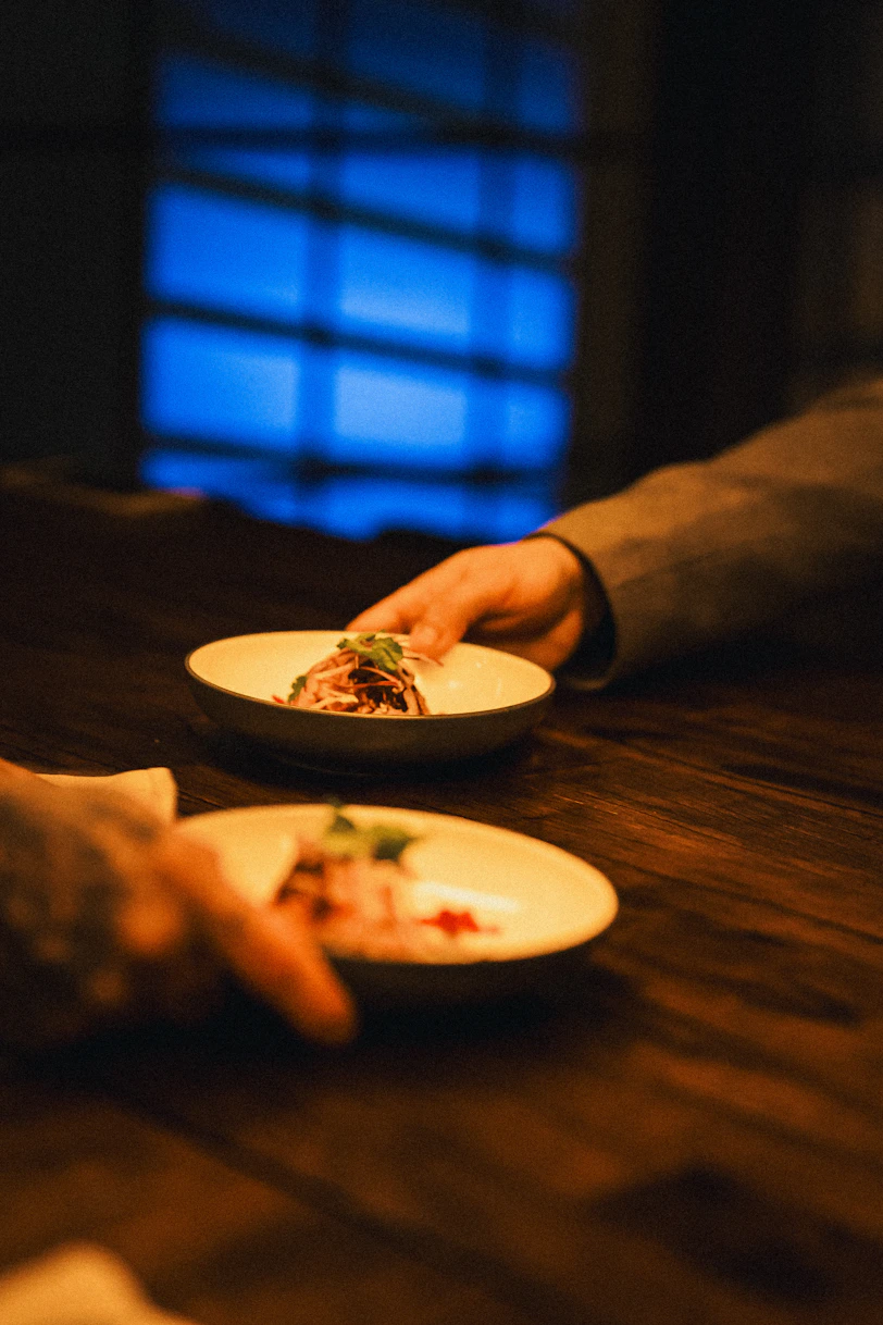 Hands reach for plates of food at a table