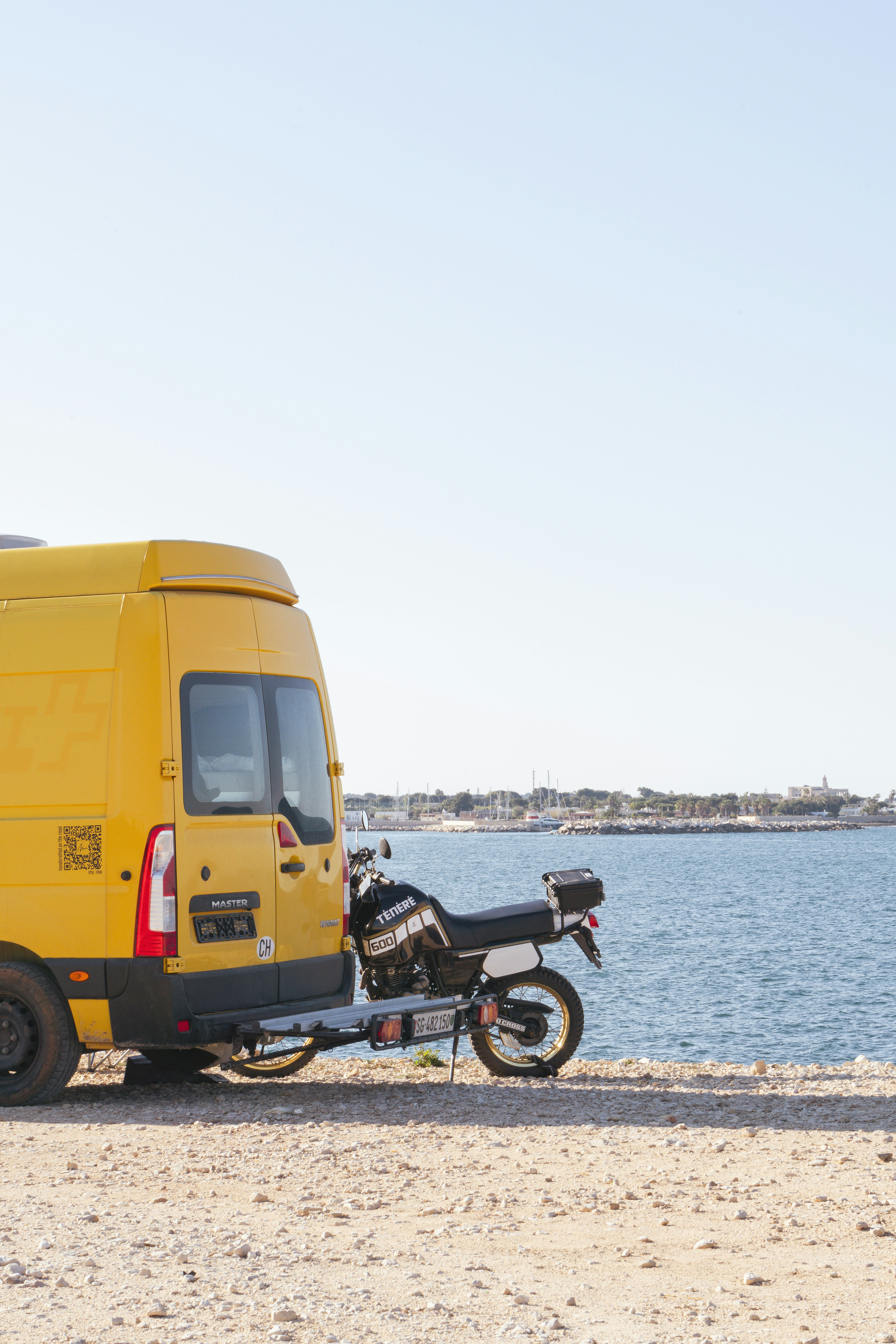 A yellow van carries a motorcycle near the sea. photo – Free Beach ...