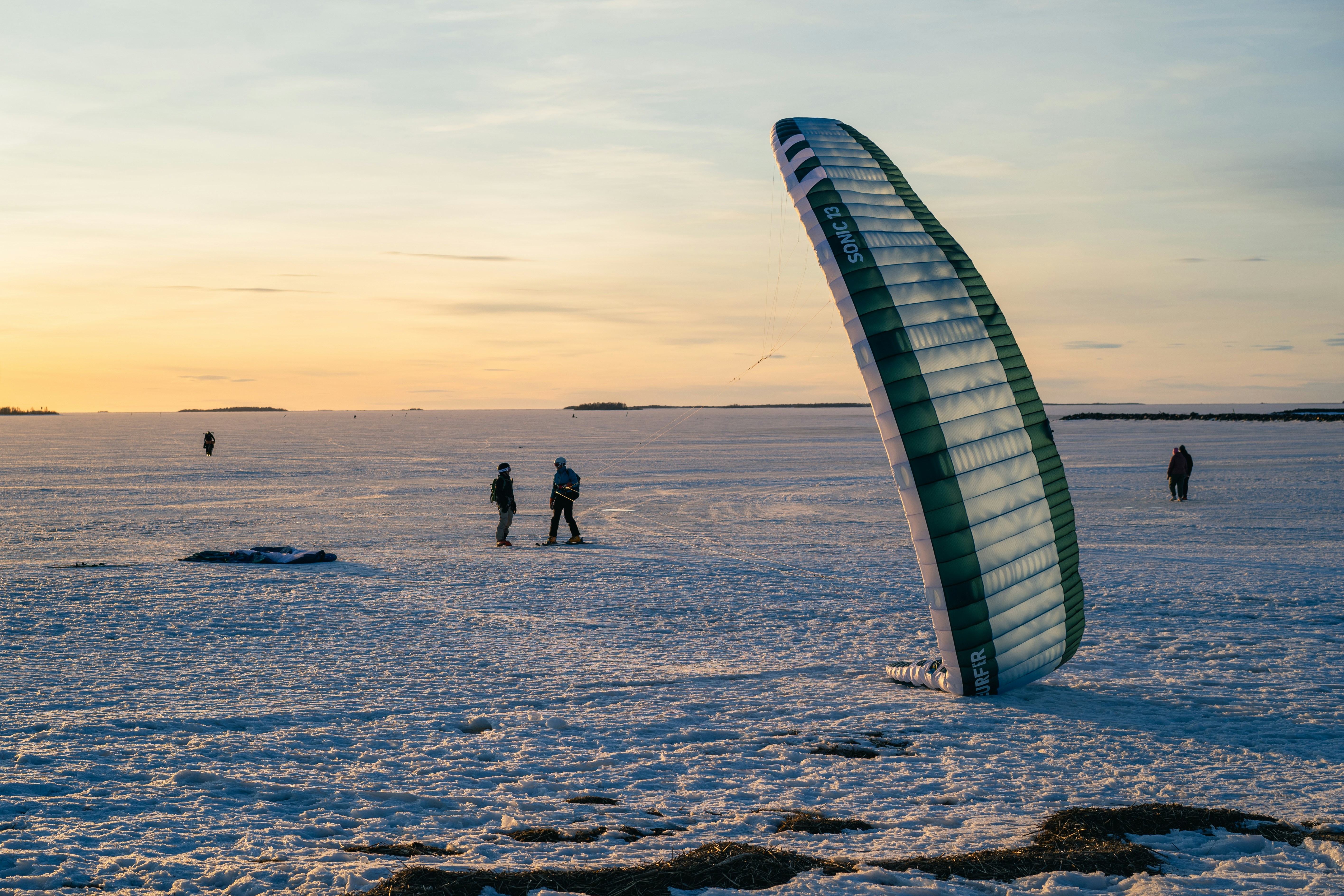 Kite-skiing on a snow-covered landscape at sunset.