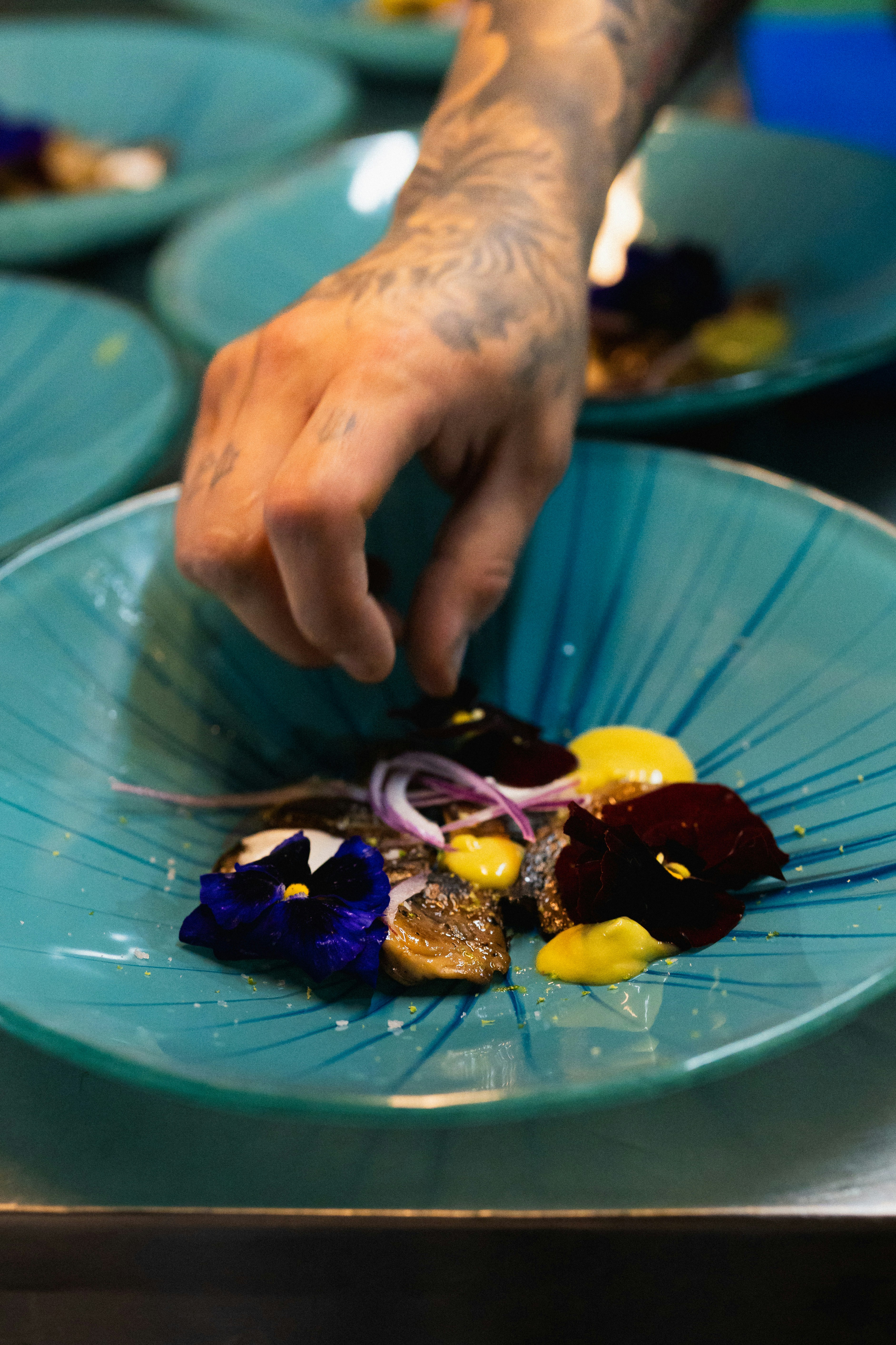Close up of a chef finishing a plate with microgreens