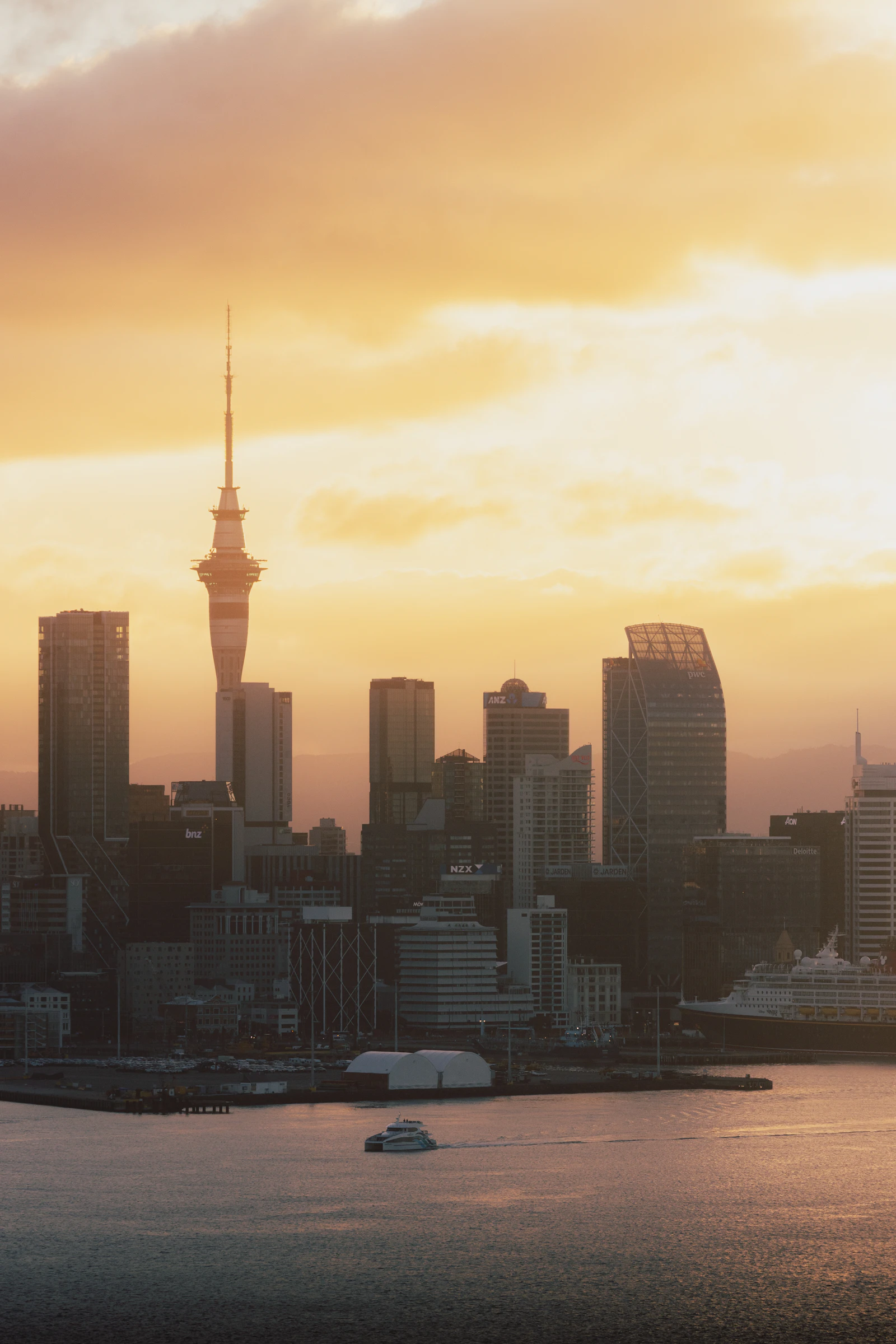 Auckland skyline and Sky Tower silhouetted at sunset, viewed from Devonport — the commercial centre of New Zealand's NZ$2.967 billion digital advertising market