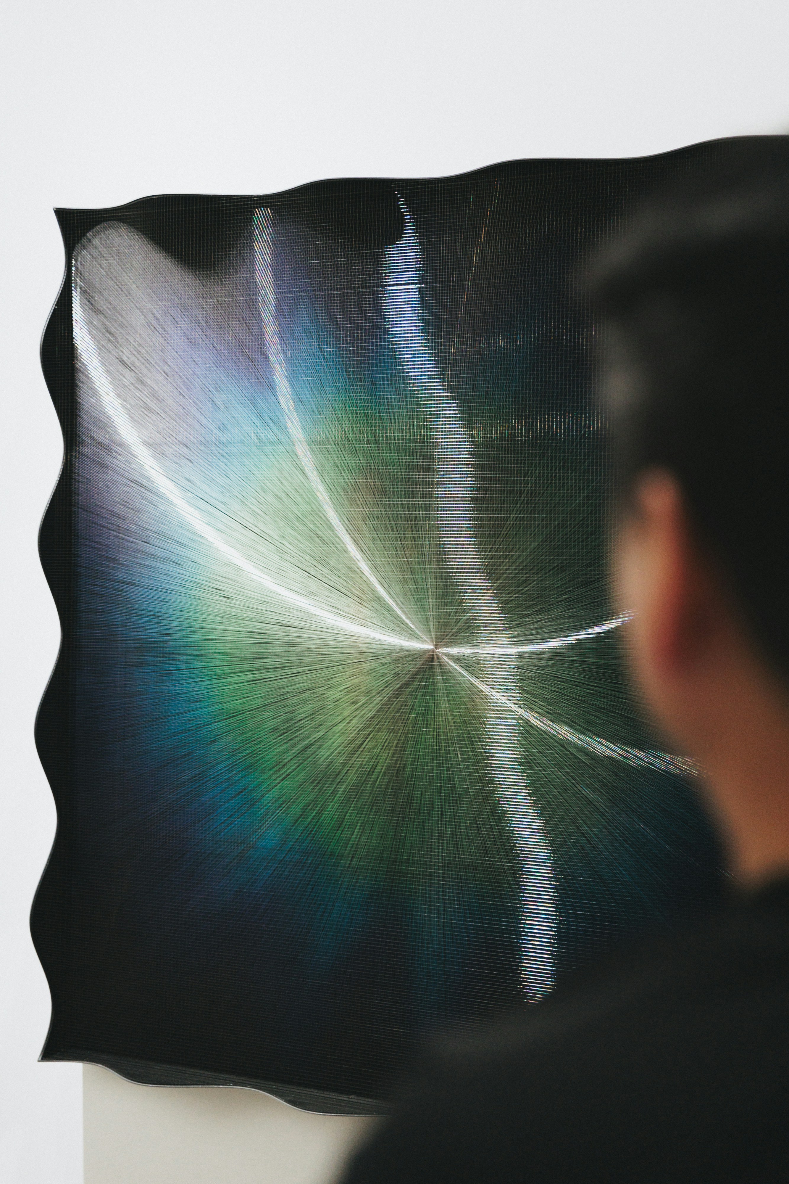 Person admires a colorful, abstract art piece.