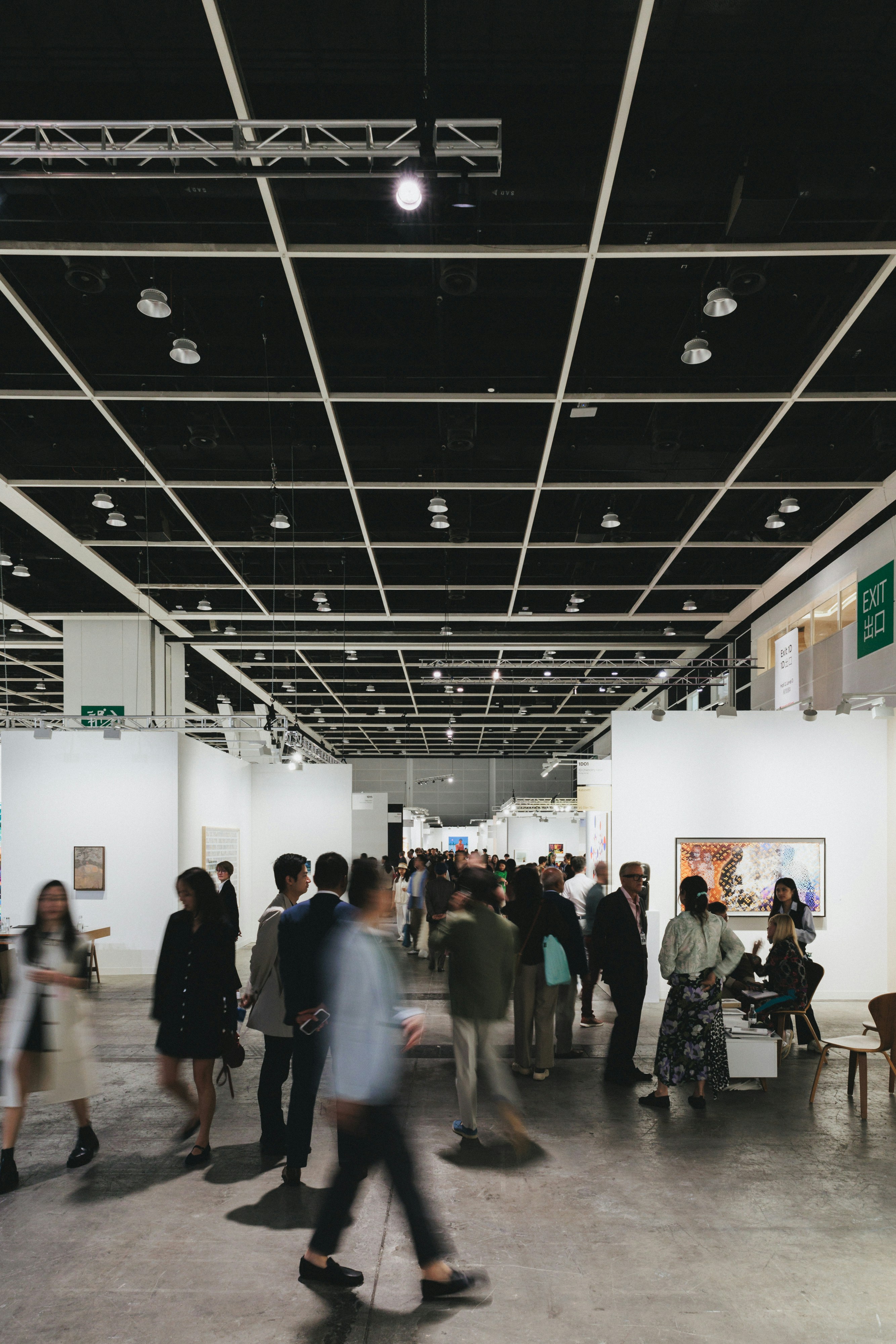 People are walking through a large art gallery.