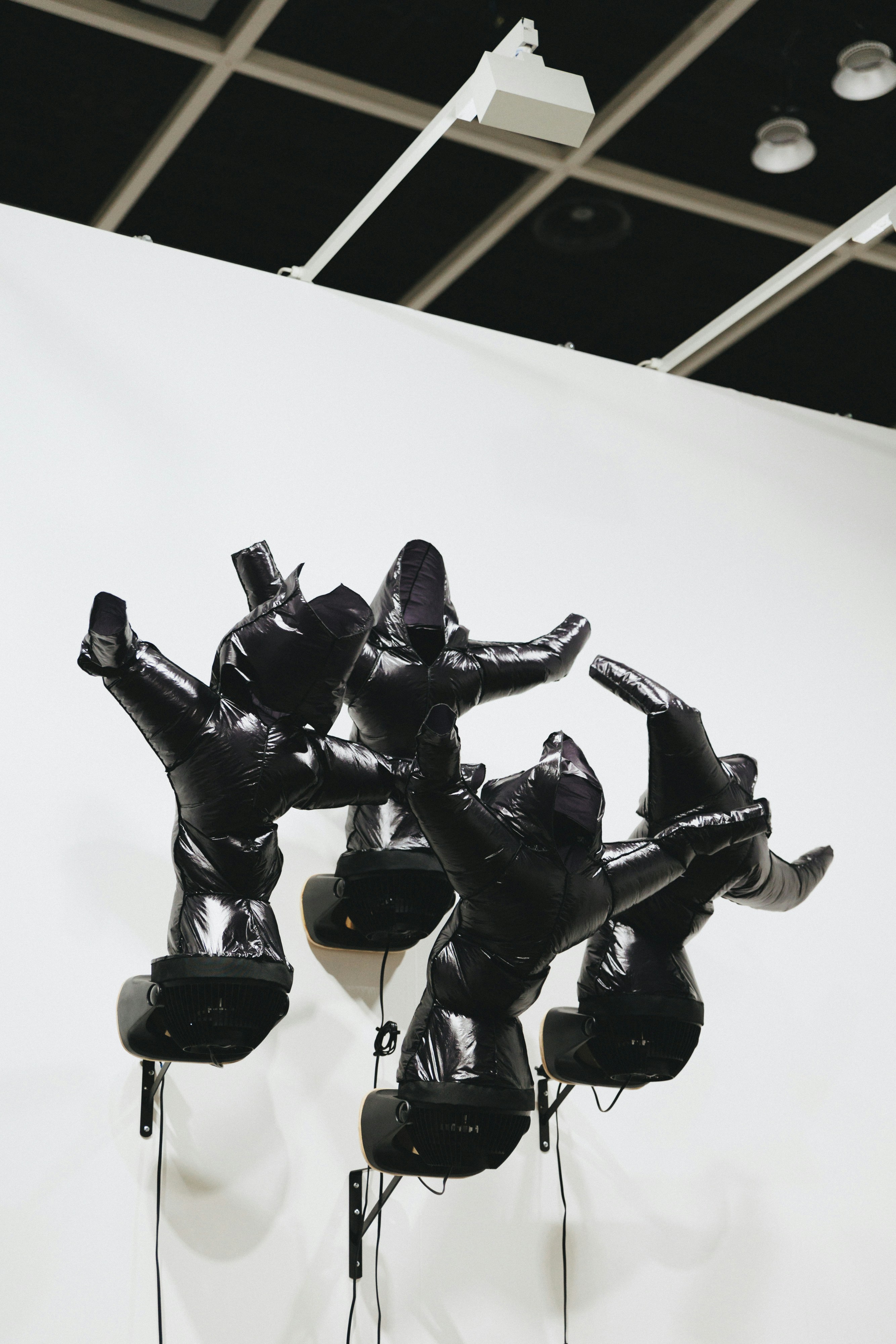Black sculptures are mounted on a white wall.