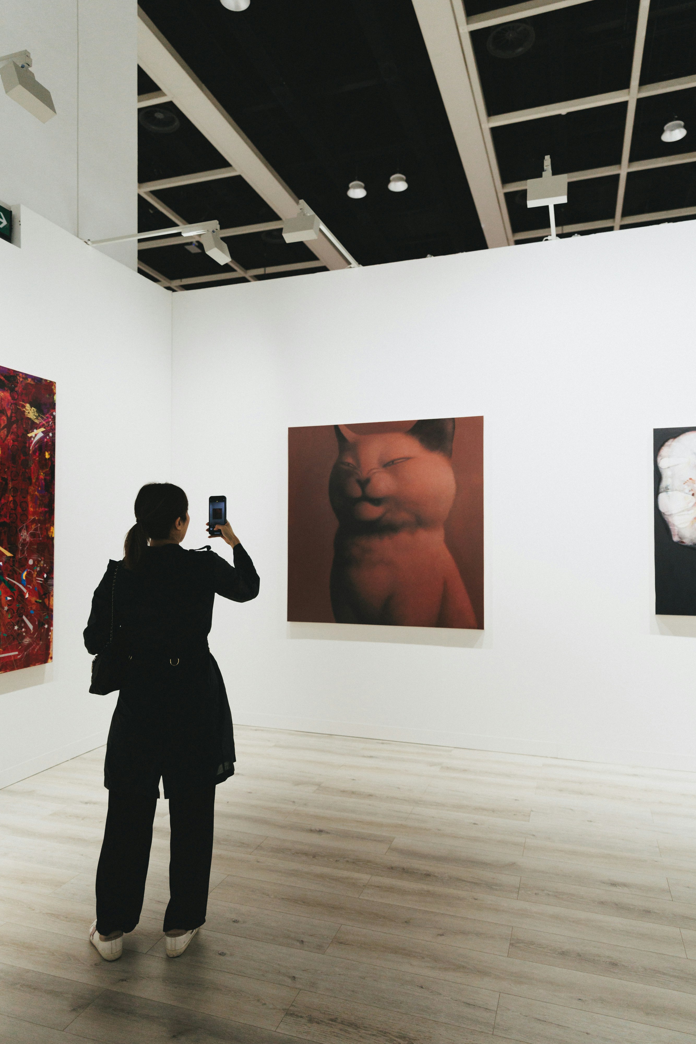 A woman takes photo of art in a gallery.