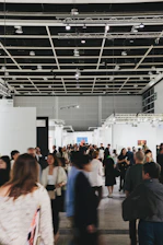 People browse art in a busy, modern gallery.