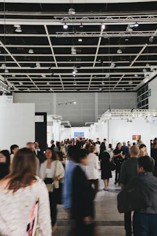 People browse art in a busy, modern gallery.