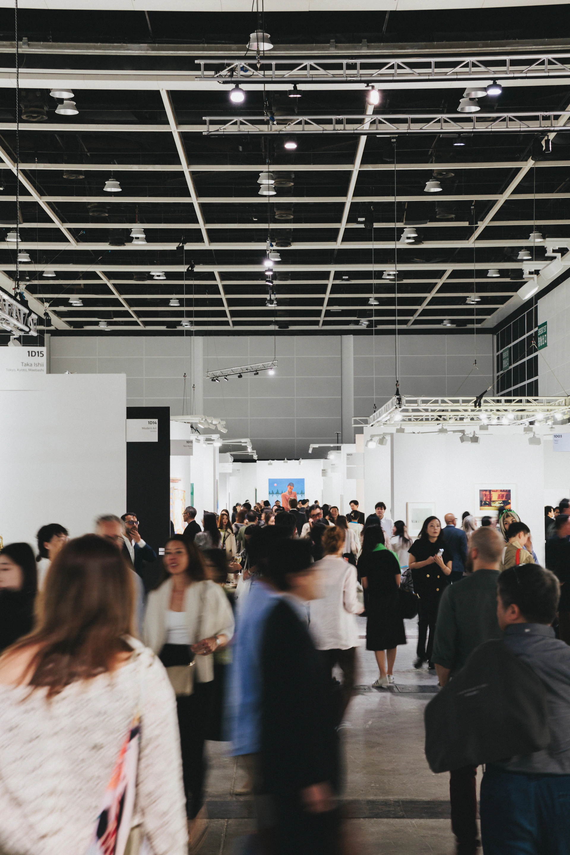 People browse art in a busy, modern gallery.
