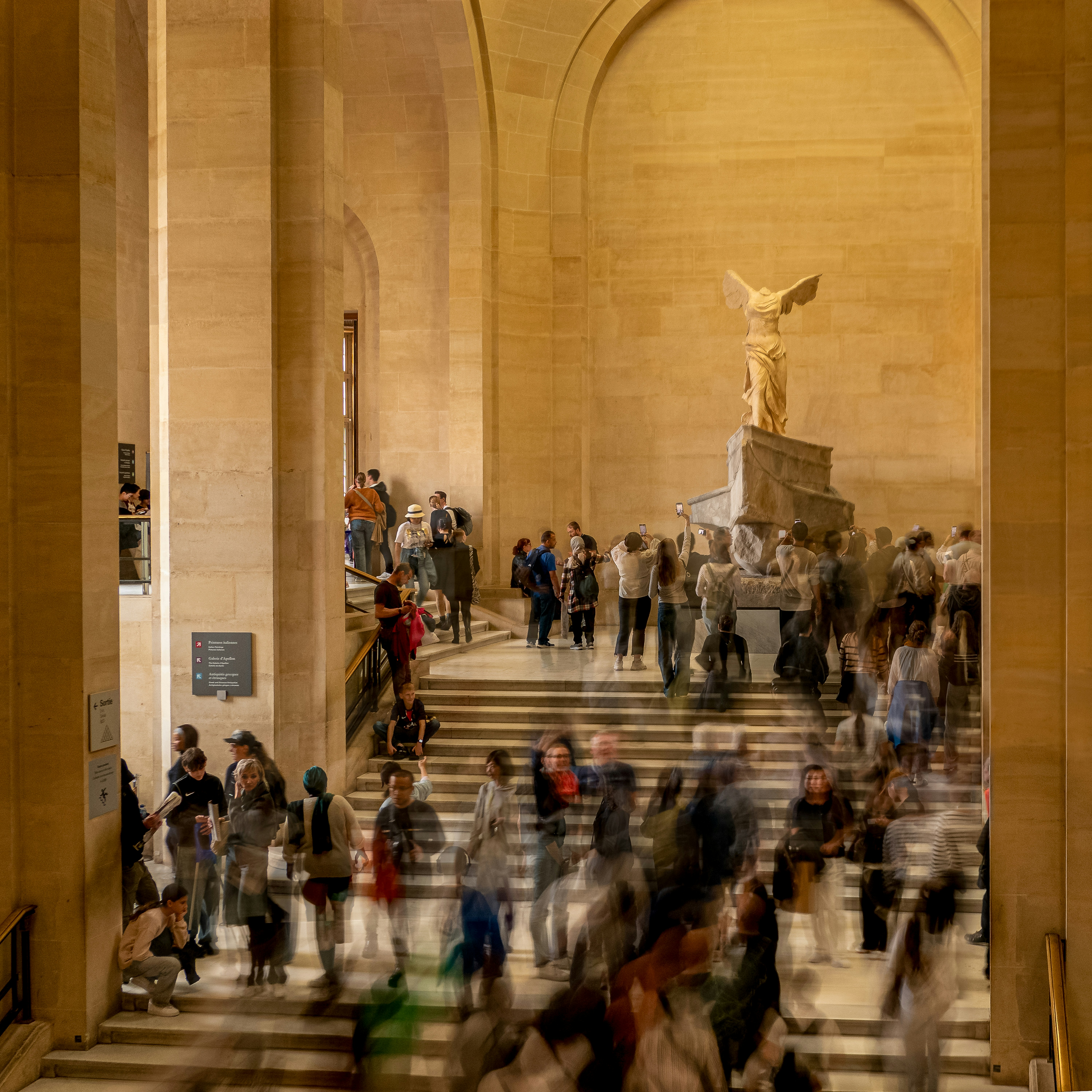 博物館の像の周りをうろつく人々。
