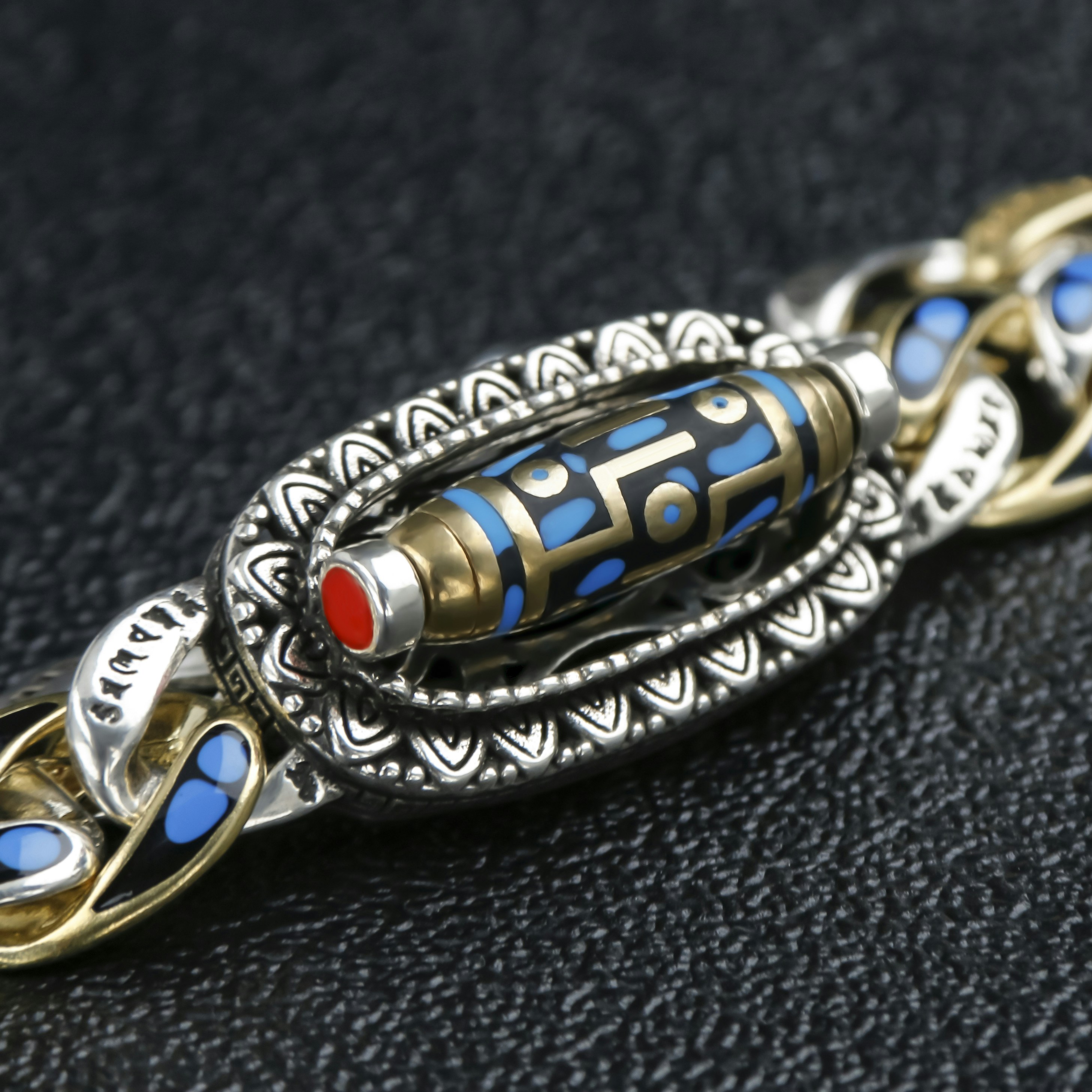 Pulsera ornamentada con eslabones de oro y plata sobre un fondo texturizado.