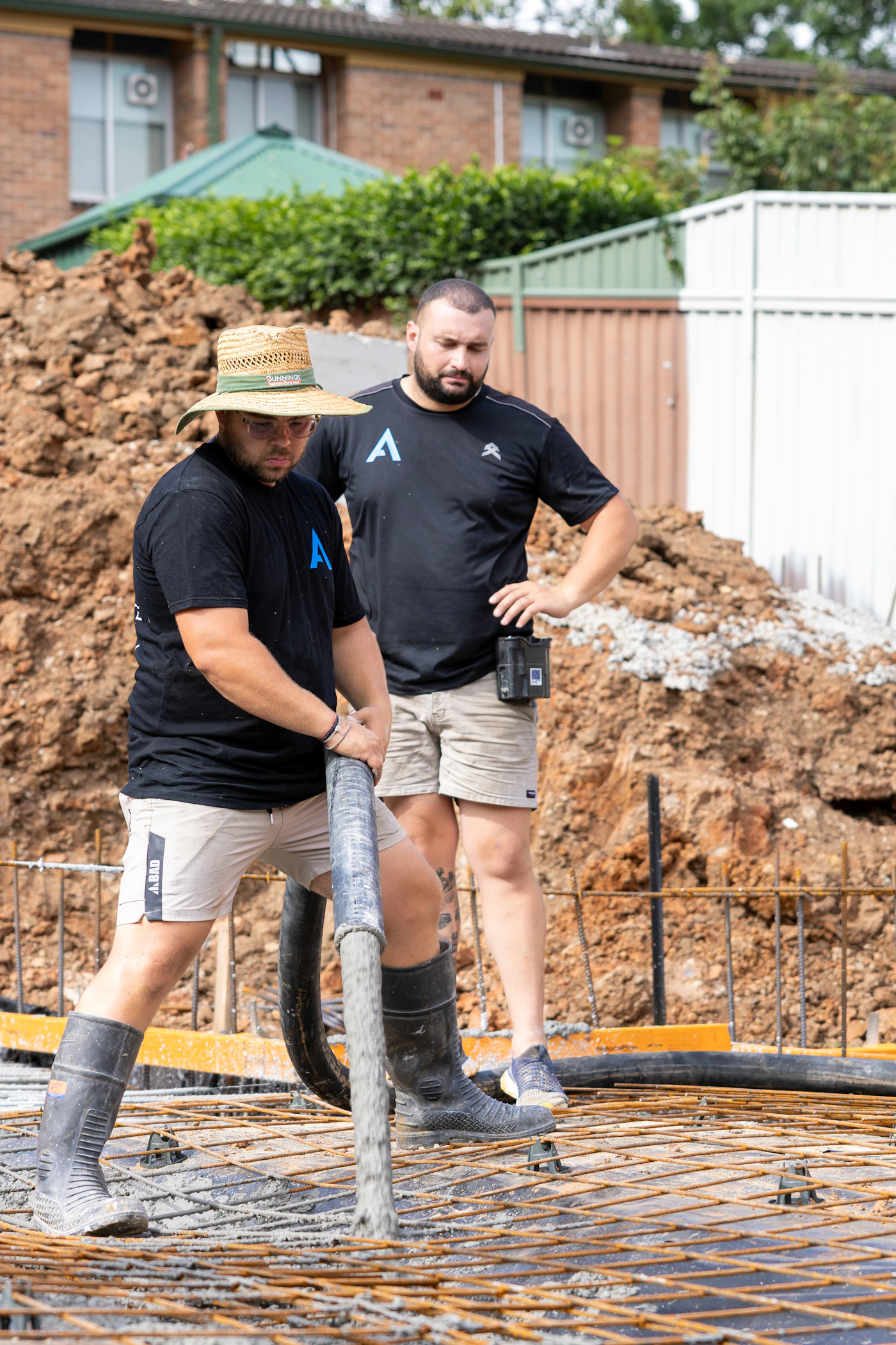 Workers pouring concrete over rebar for a foundation slab