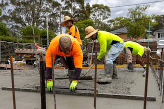 Construction workers pouring and leveling concrete.