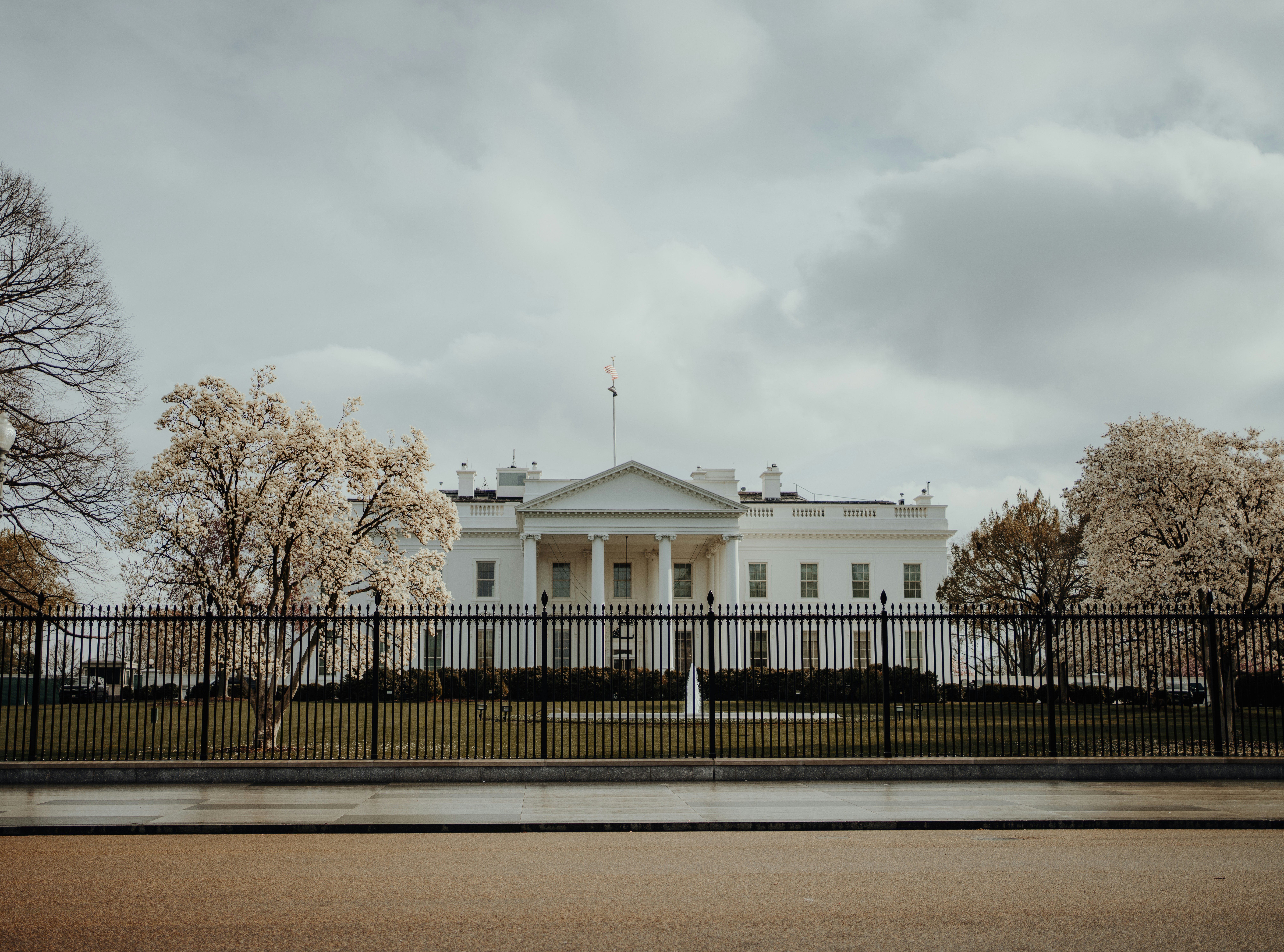 The white house stands behind a fence.