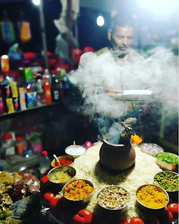 Street vendor prepares food with steaming smoke.
