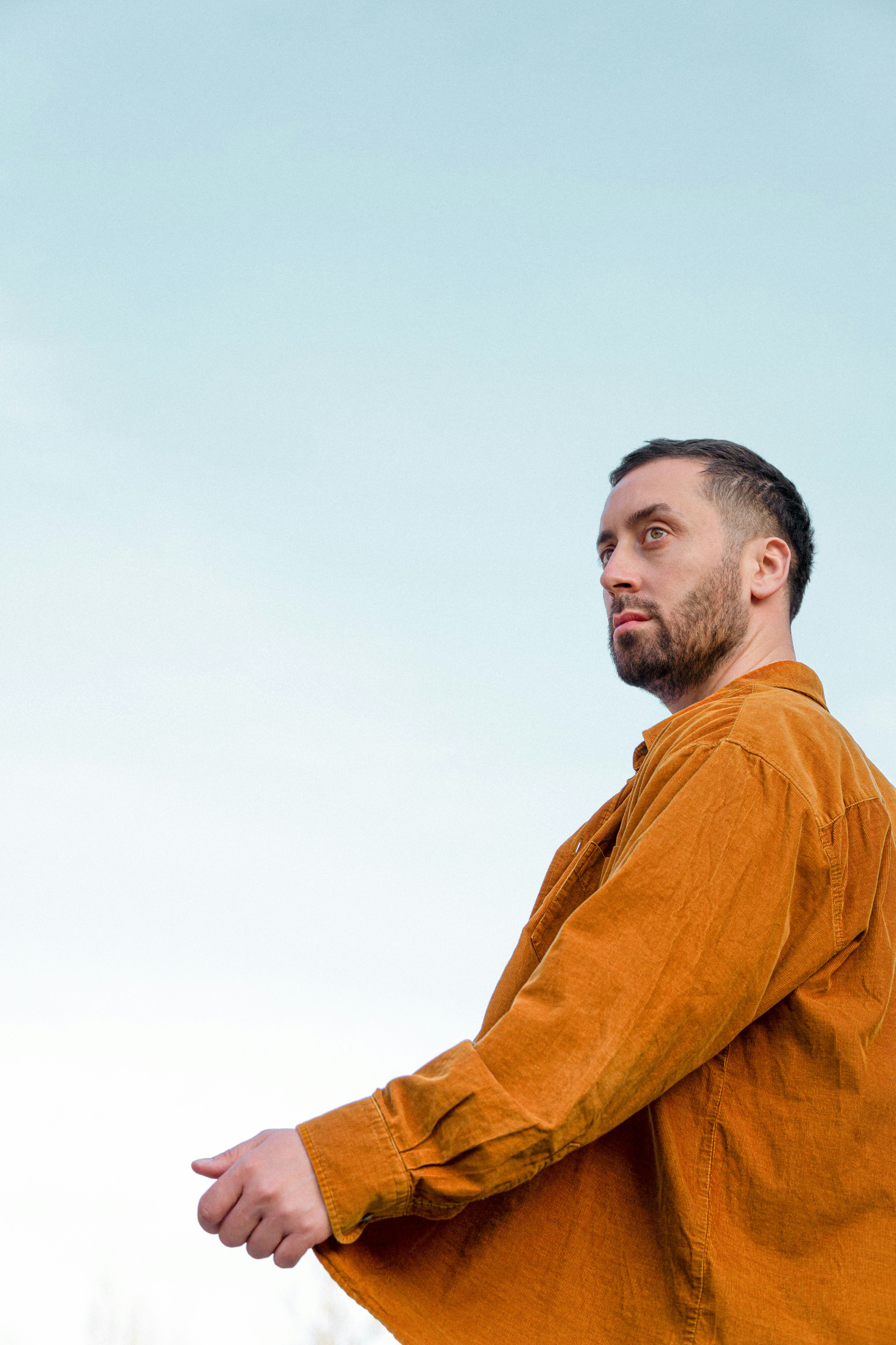 Uomo in camicia arancione che guarda verso il cielo.