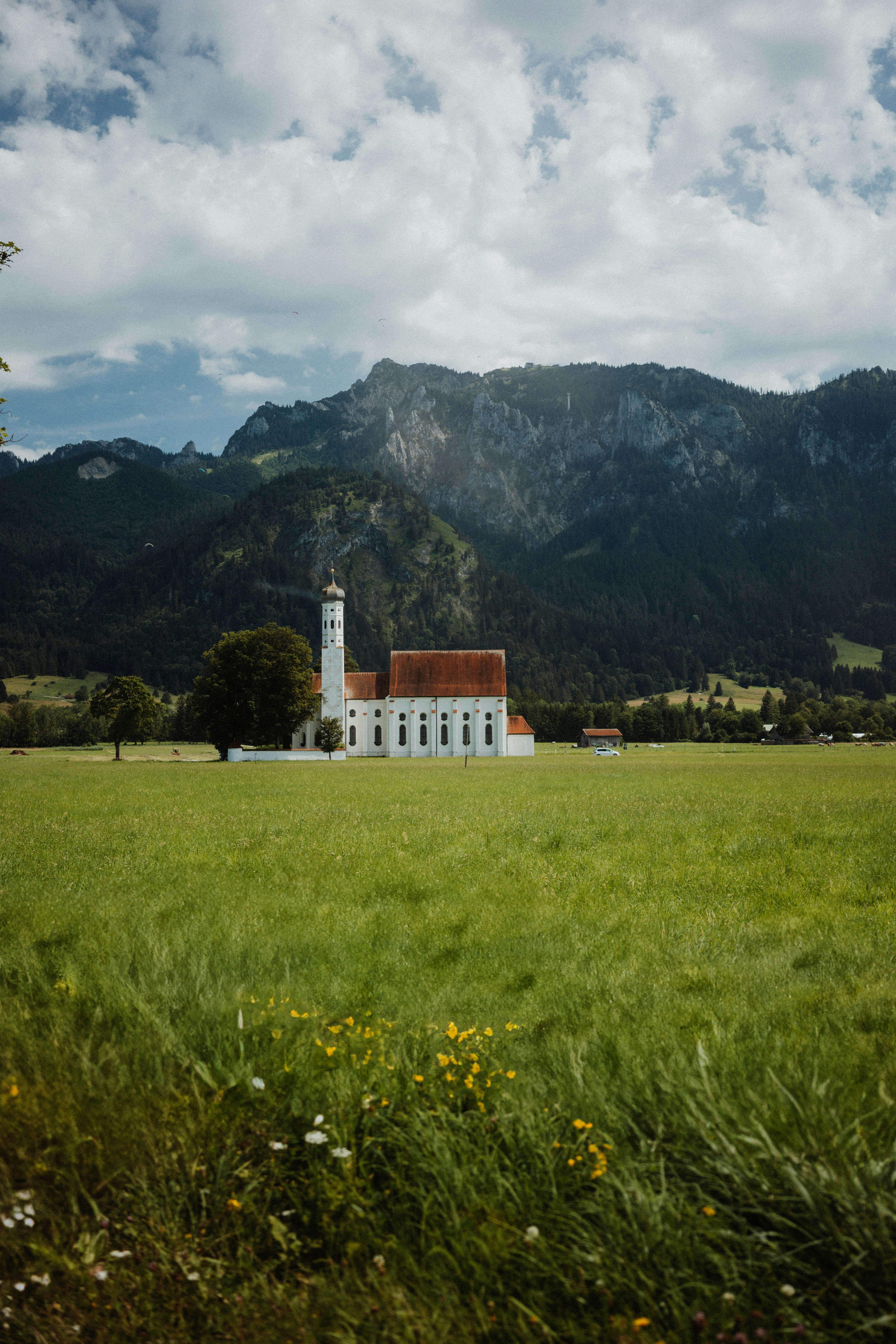 Église dans un champ avec des montagnes en arrière-plan.