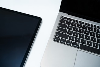 A tablet and laptop on a white surface.