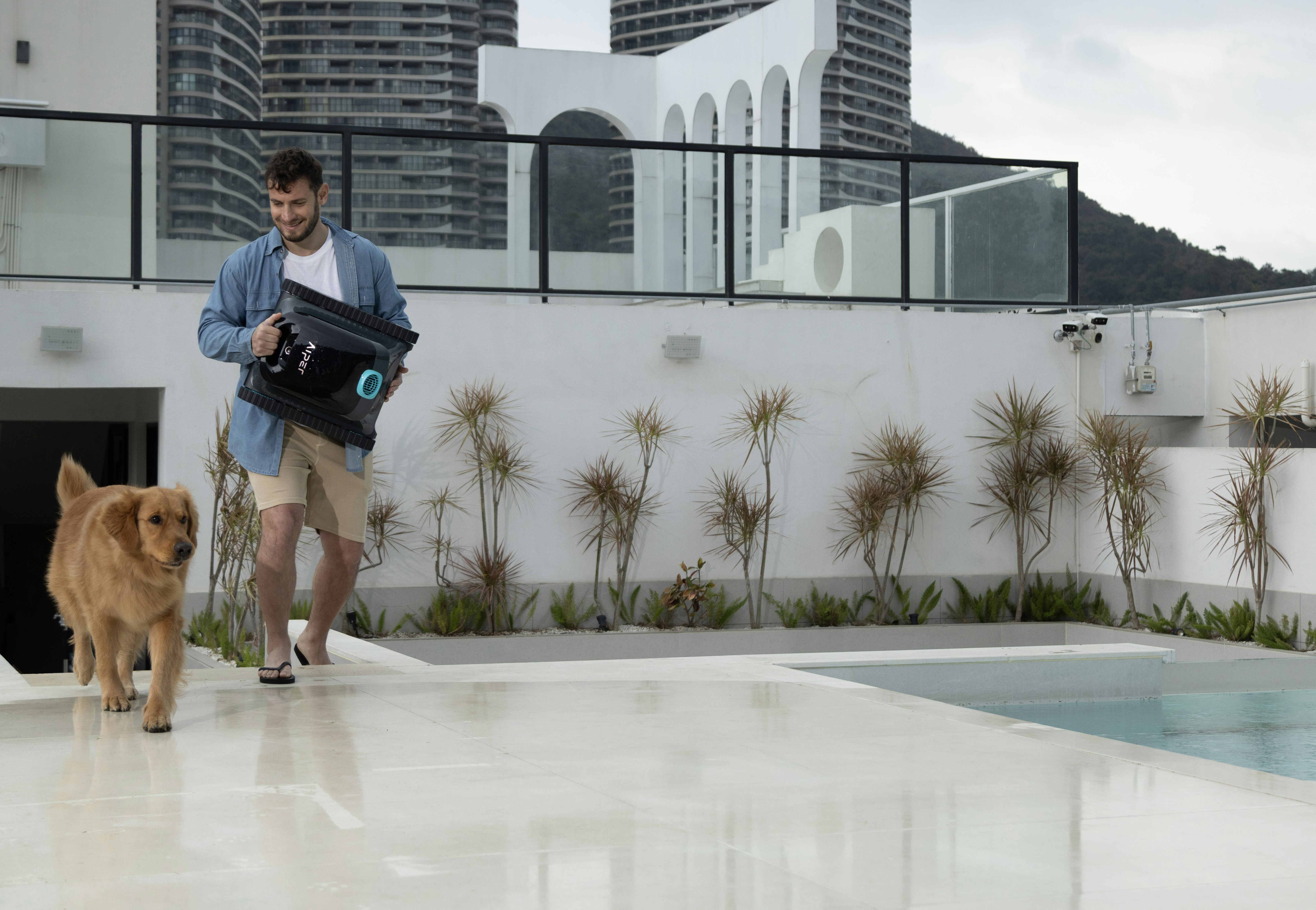 Man and dog walk alongside a pool.