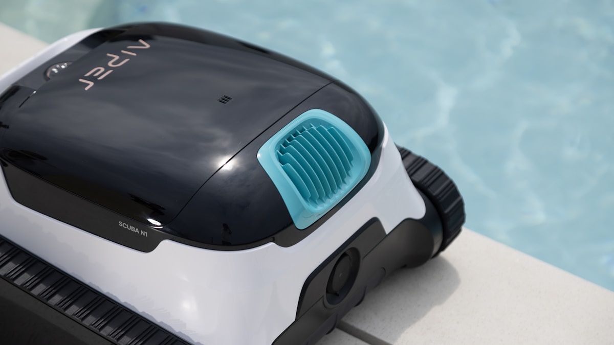 A robotic pool cleaner sits by the pool.