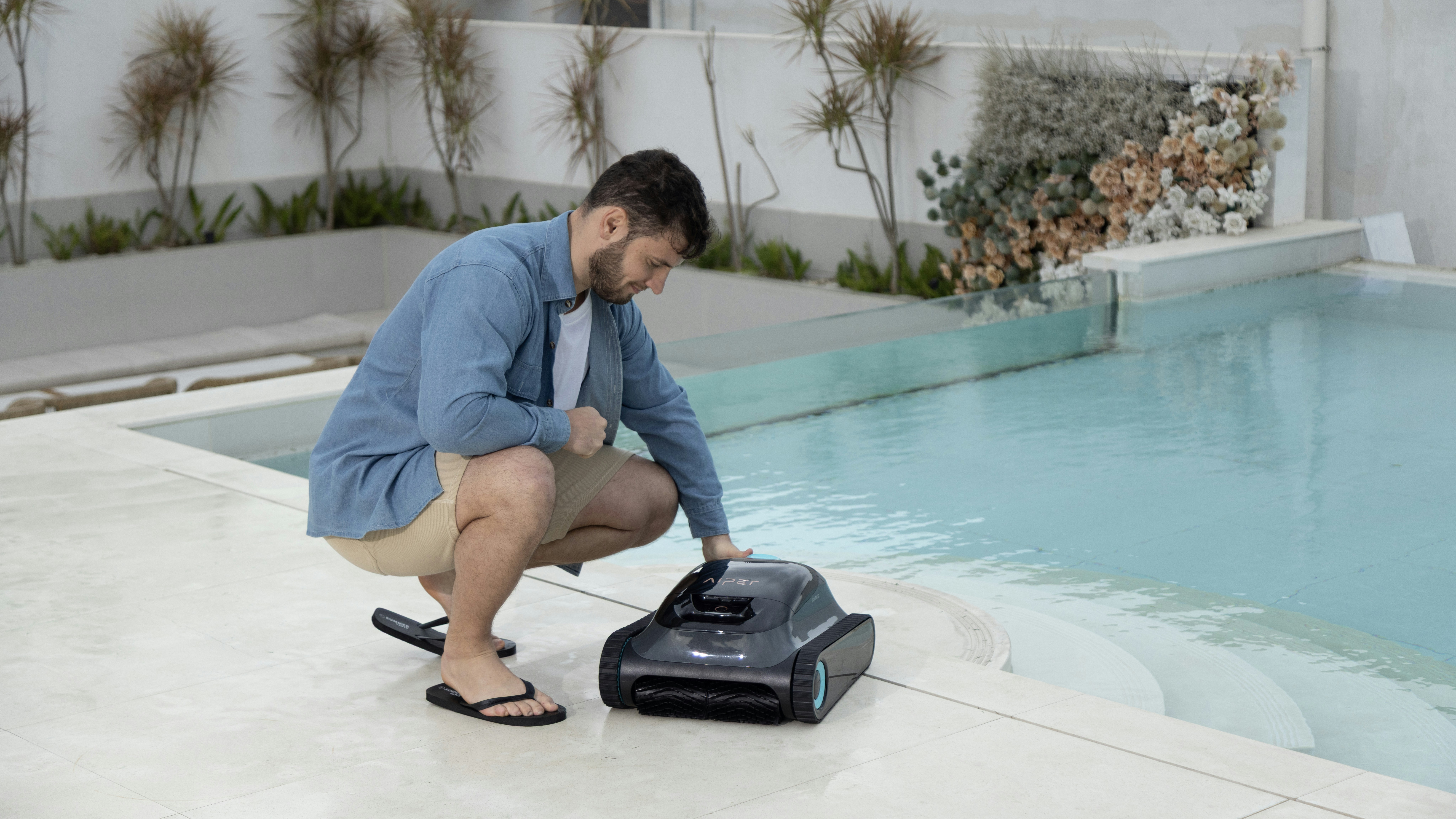 A man is deploying a robotic pool cleaner.