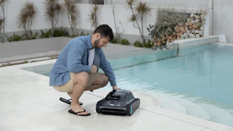 A man is deploying a robotic pool cleaner.