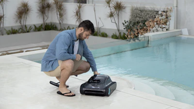A man is deploying a robotic pool cleaner.