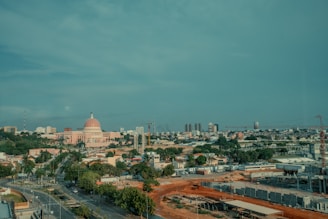 A cityscape is under a cloudy blue sky.