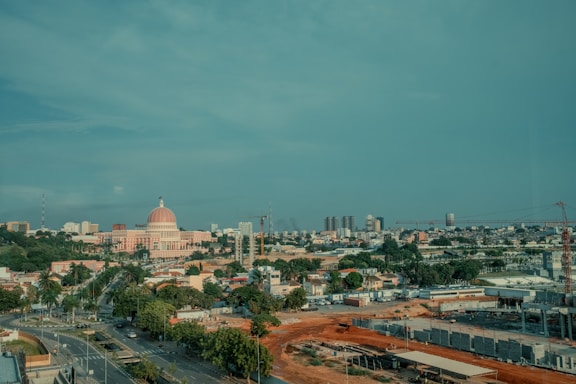 A cityscape is under a cloudy blue sky.