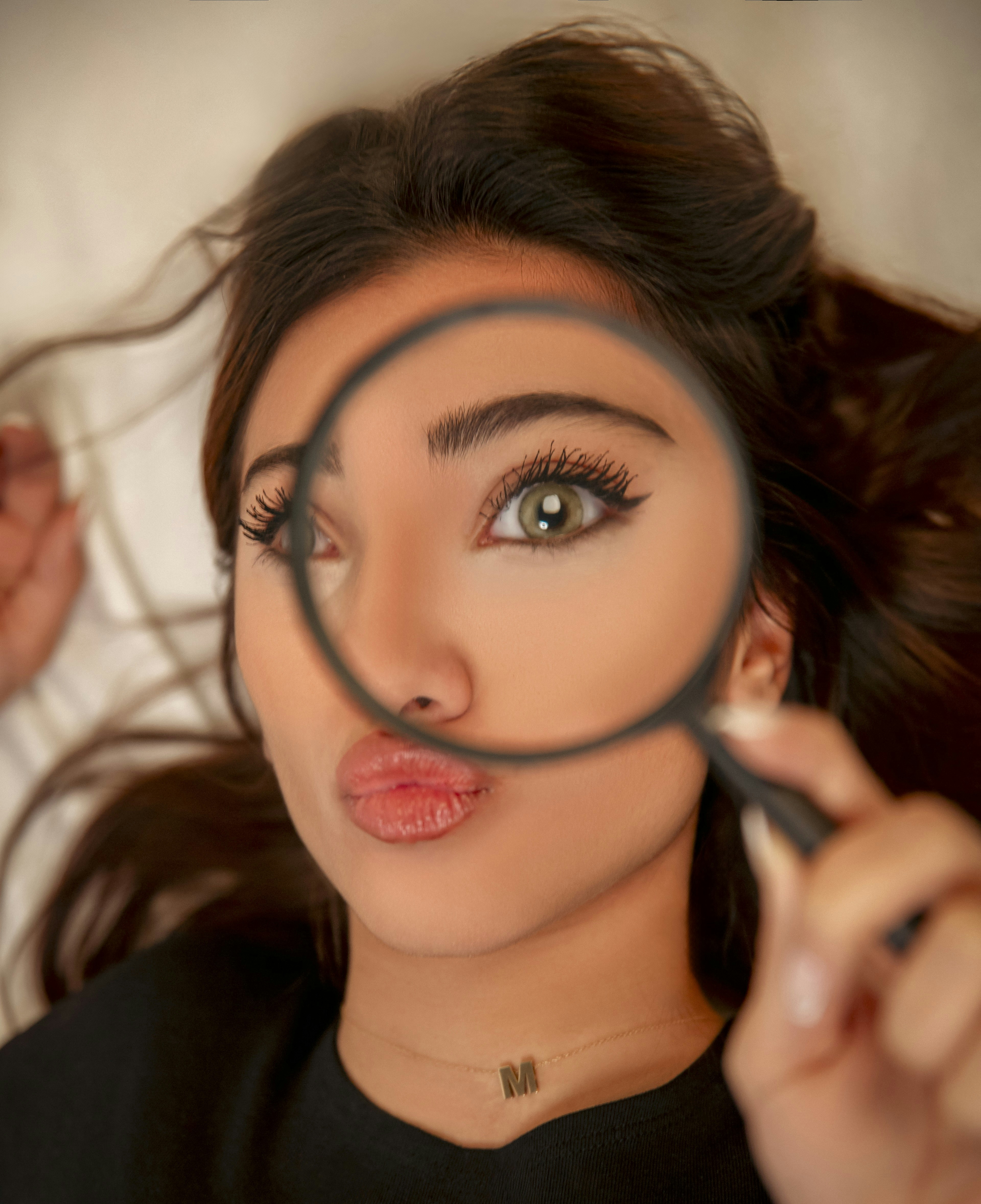 Woman peers through a magnifying glass.