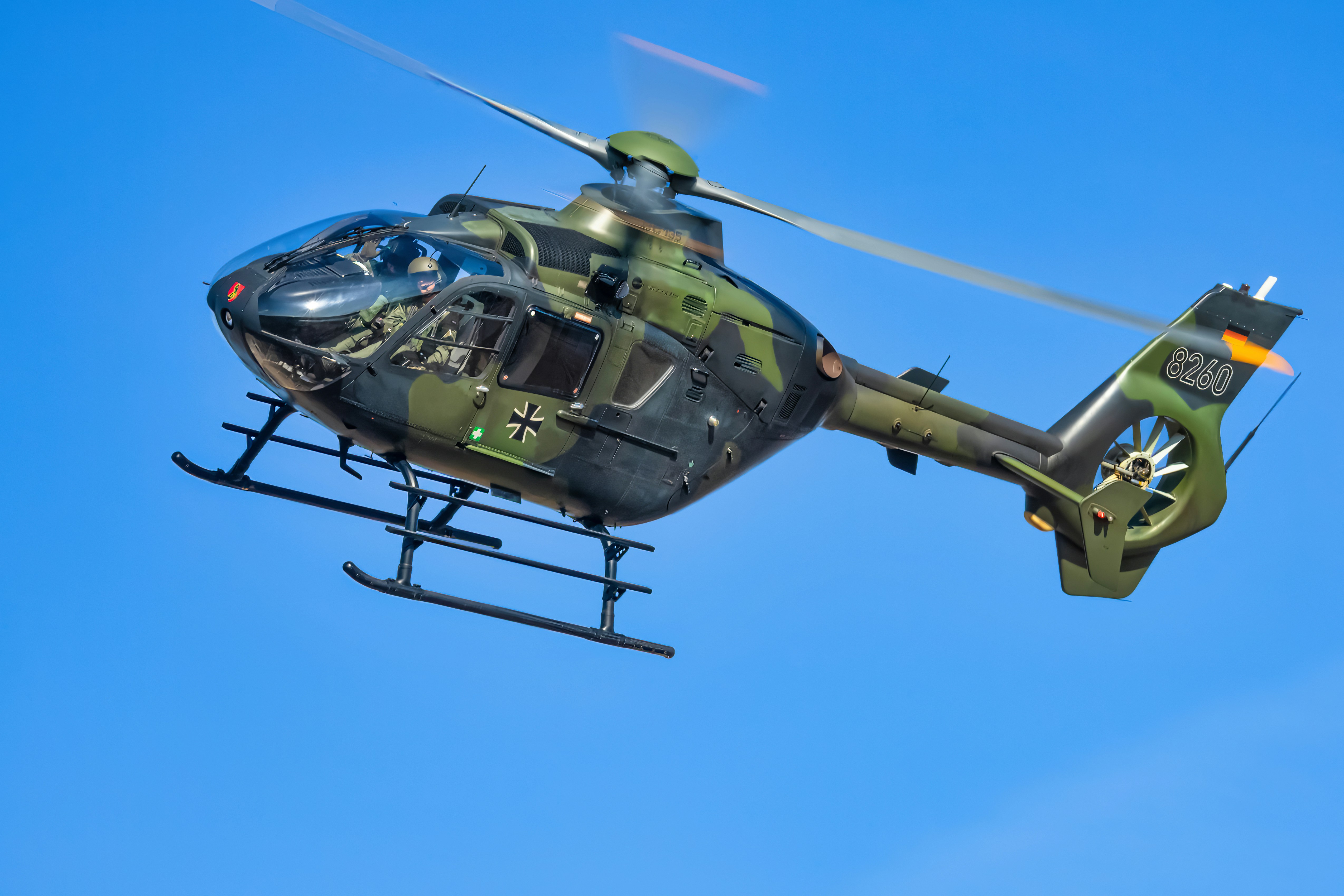 Ein deutscher Hubschrauber fliegt gegen den blauen Himmel.