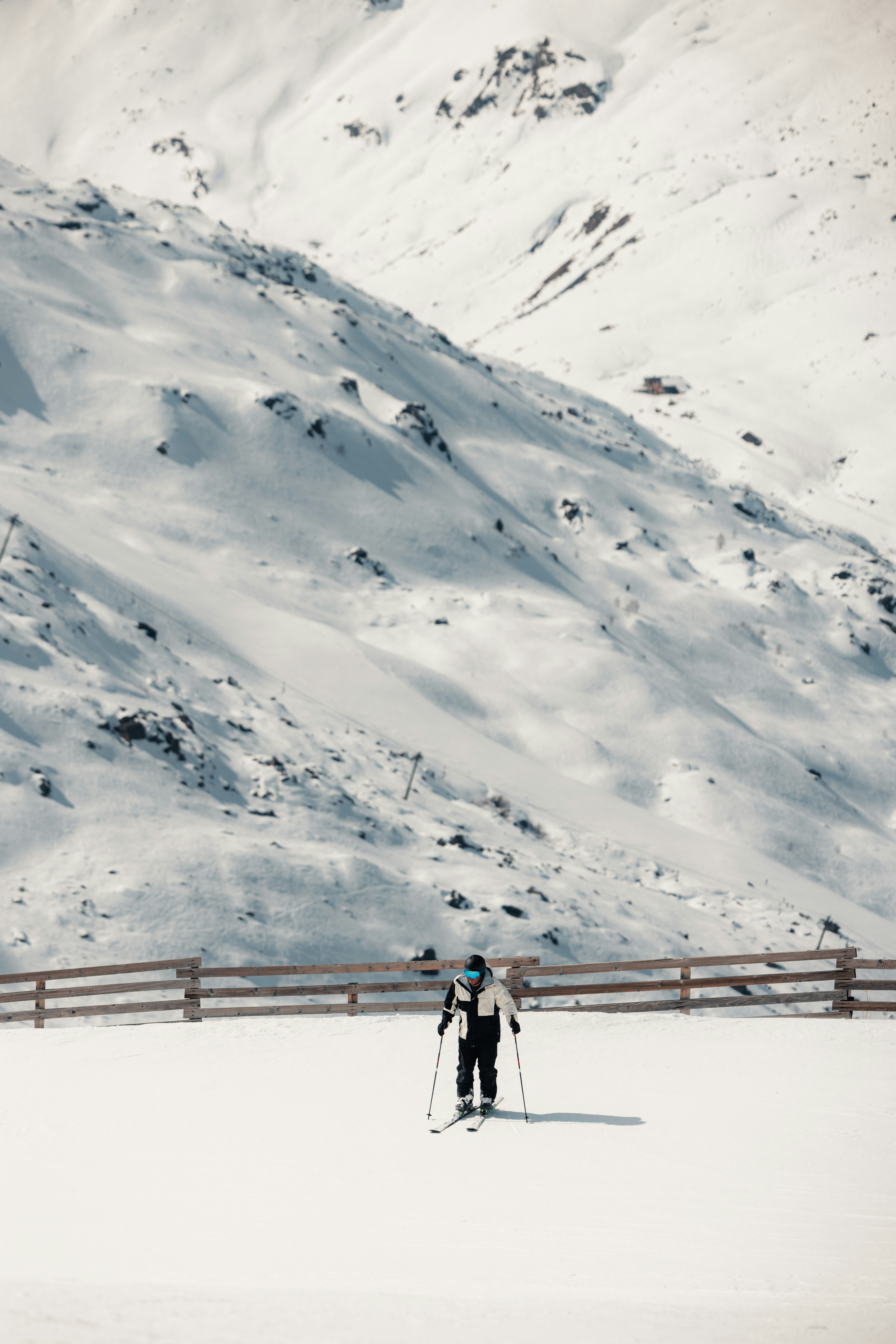 Skier stands on the snow with snowy mountains.