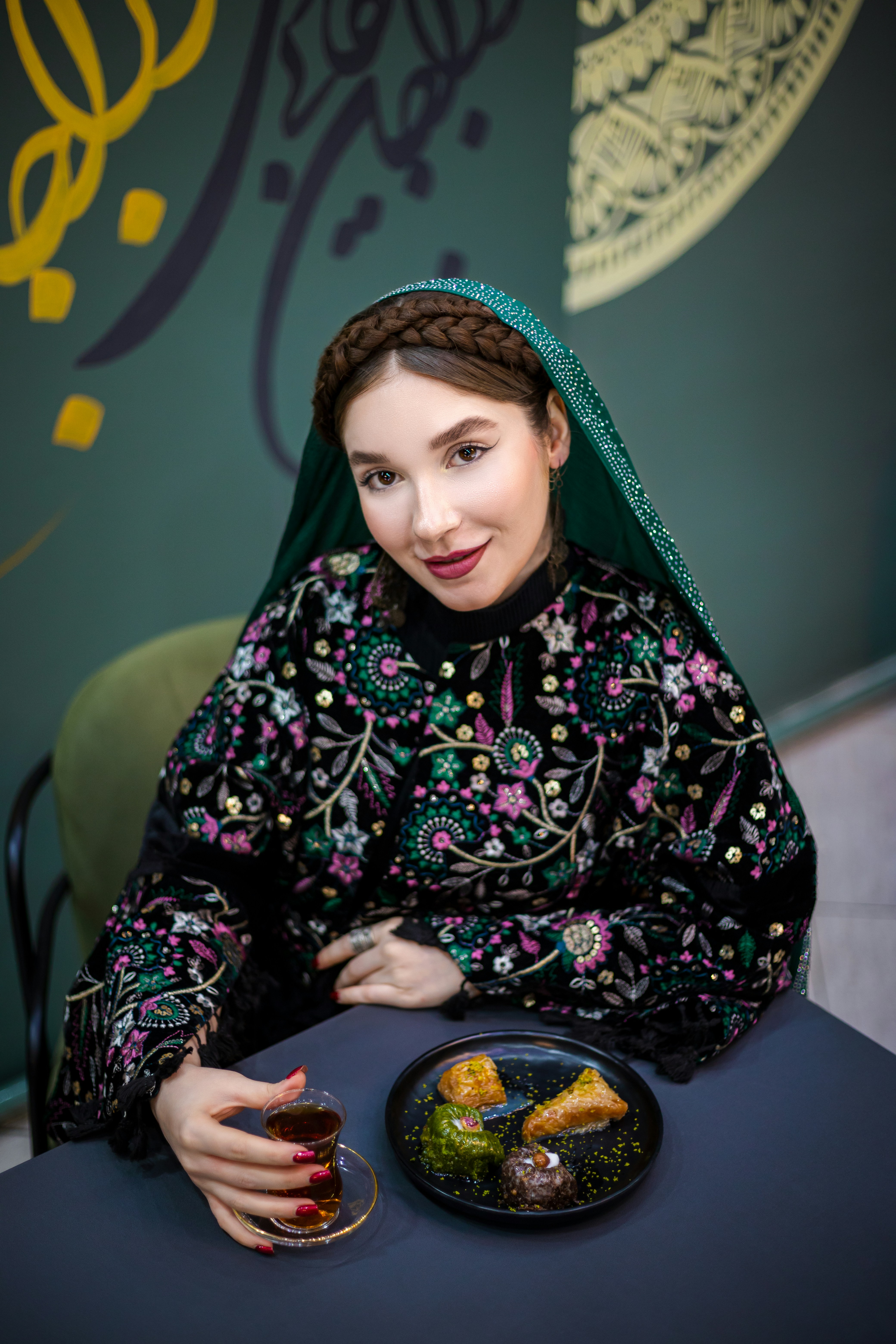 Wanita berpakaian tradisional menikmati suguhan.