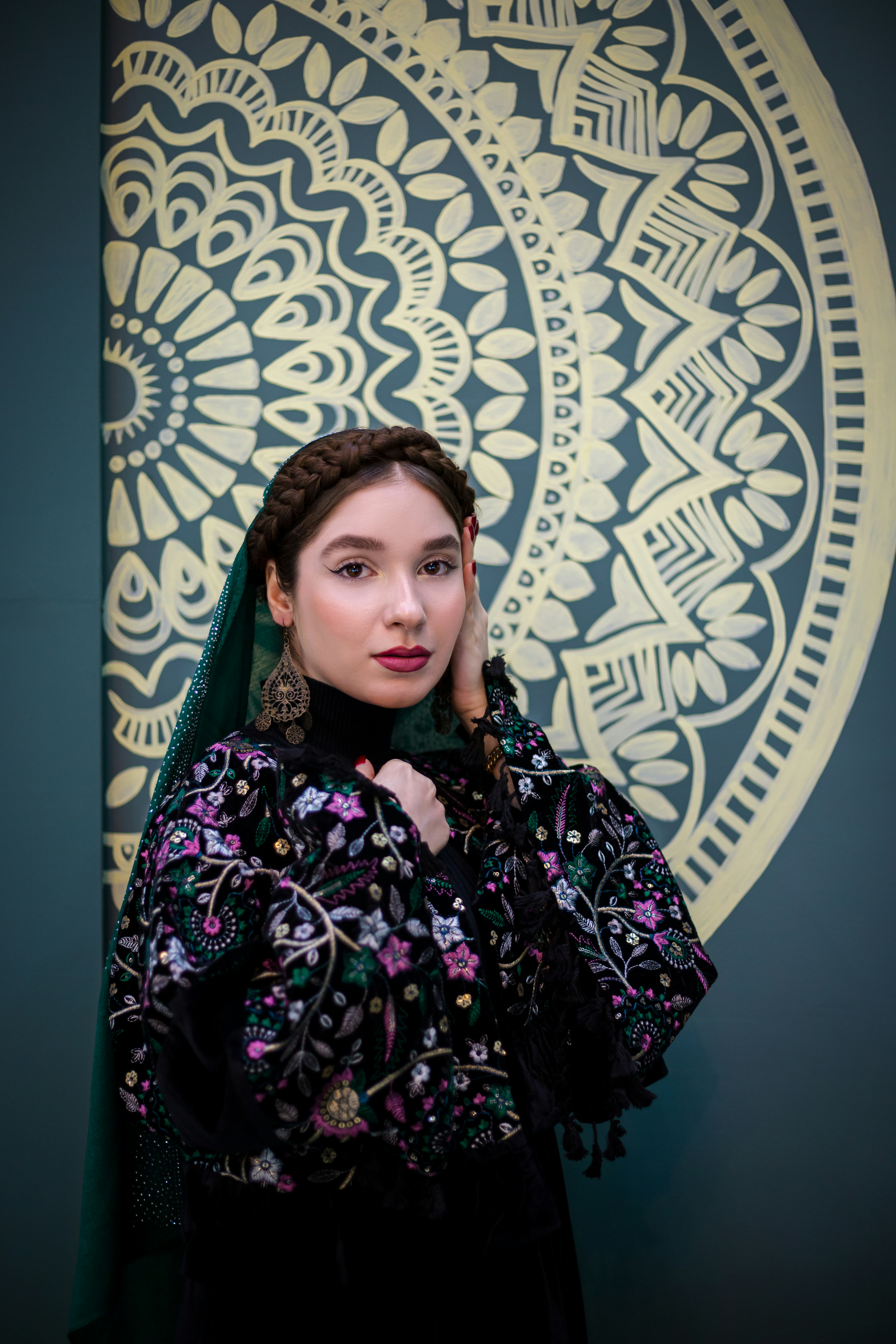 Wanita berpose di depan mural dekoratif.