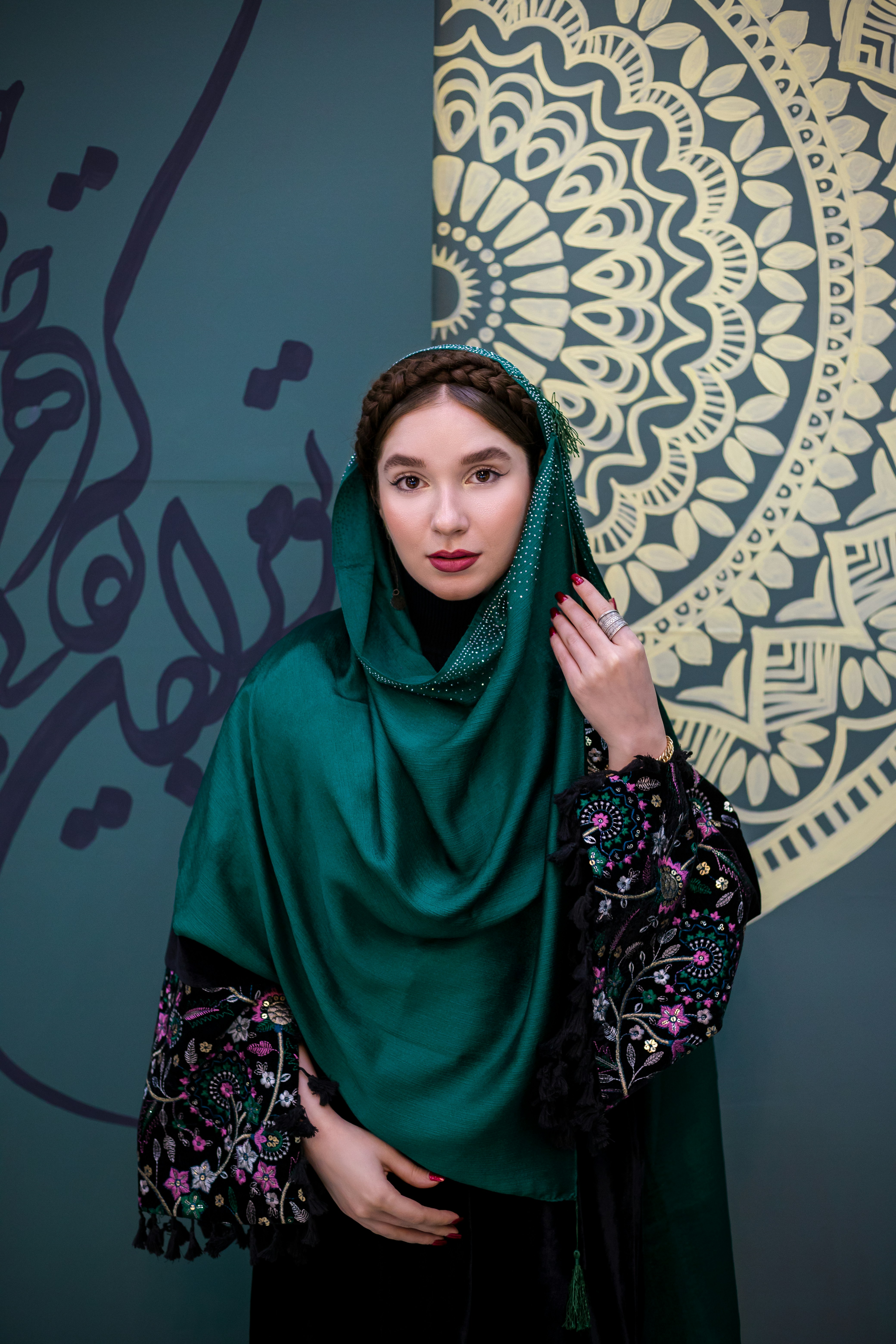 Wanita berselendang hijau berpose di depan kamera.