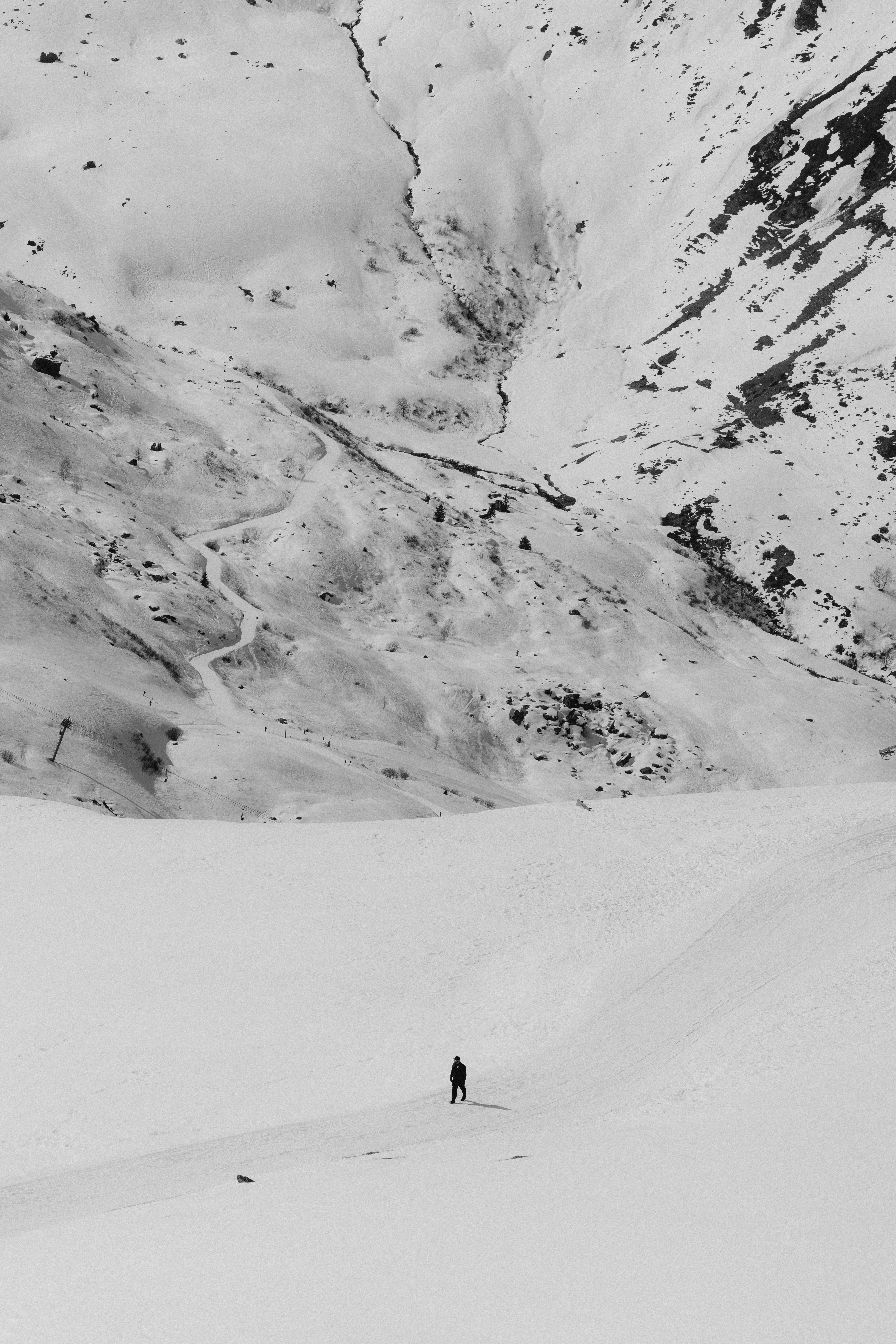 A person stands alone in a snowy mountain landscape.