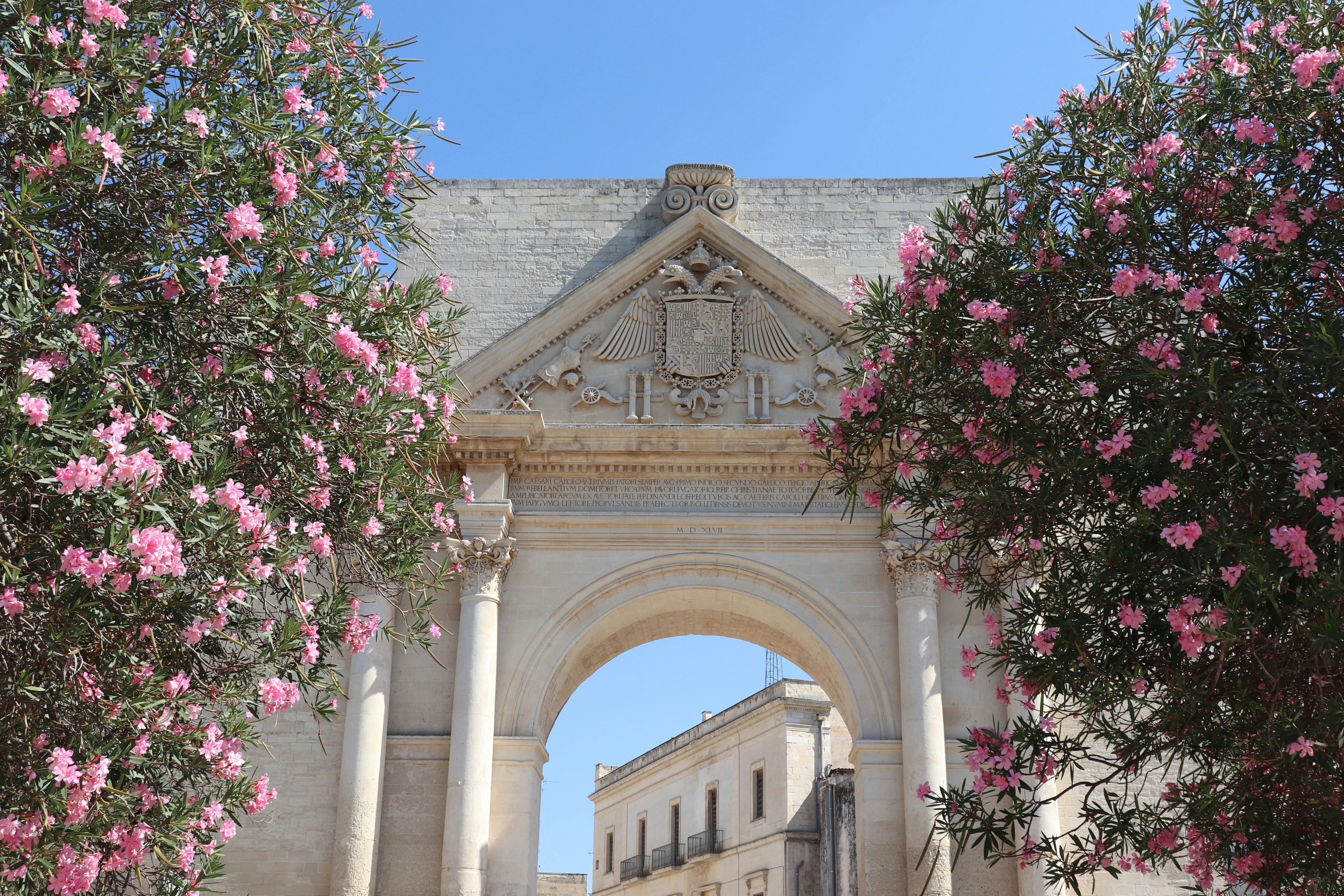 Ancient stone archway framed by pink flowers.