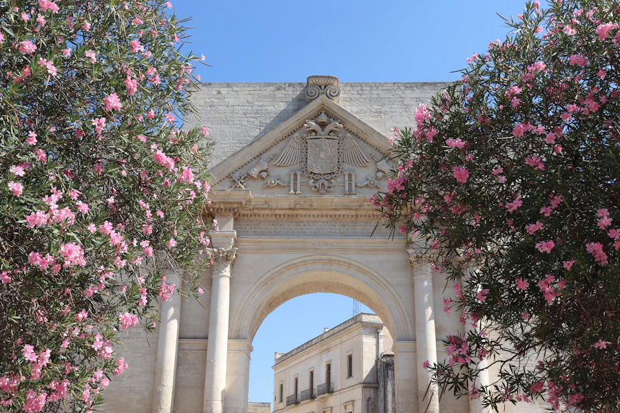 A carved stone archway framed by flowers in Lecce