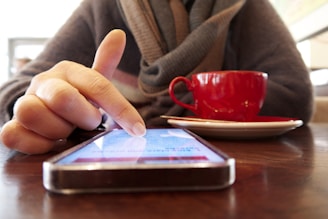 Person using a smartphone with a cup of coffee.