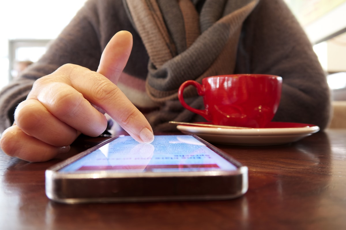 Person using a smartphone with a cup of coffee in a café