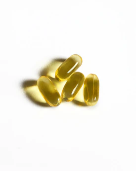 Four yellow capsules sit on a white surface
